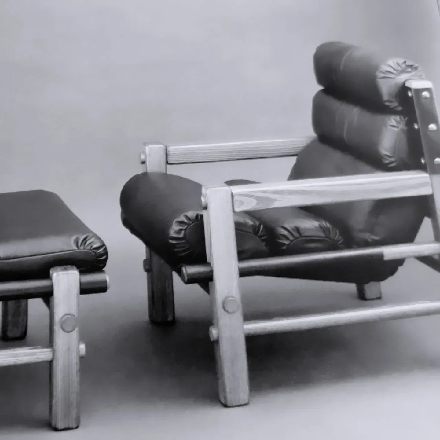 Modern wooden lounge chair with black leather cushion and matching ottoman