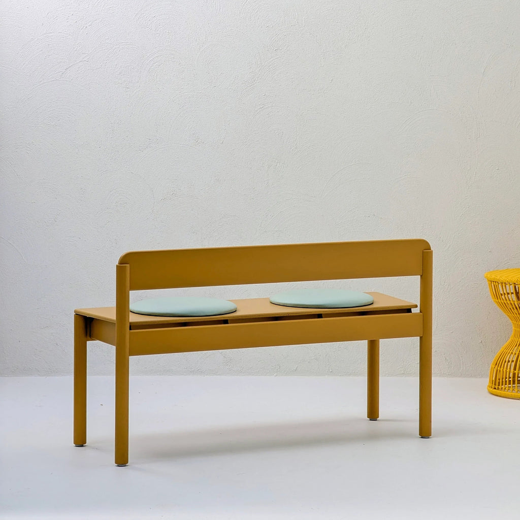 Modern yellow bench with two light blue cushions in a minimalist indoor setting