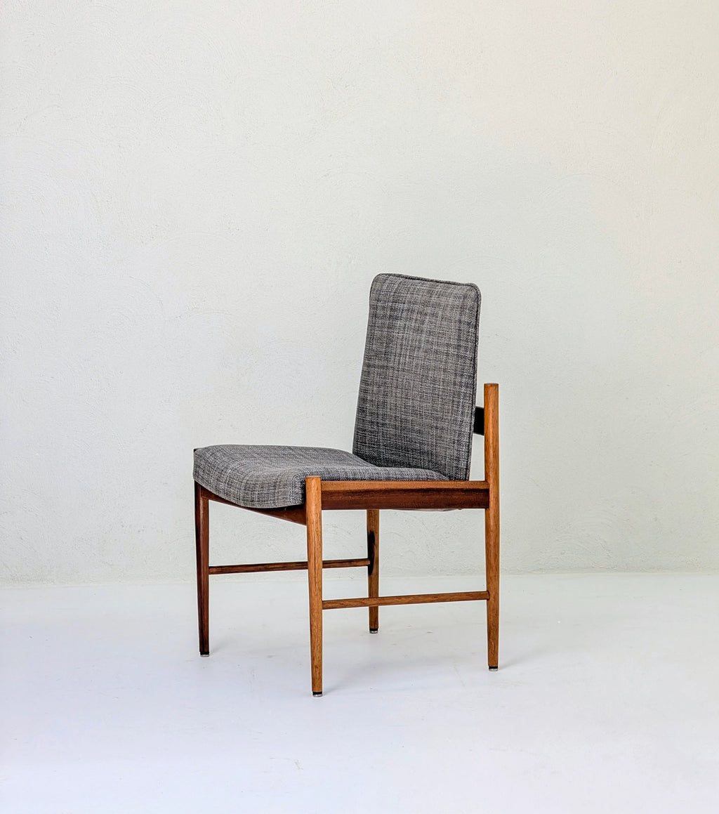 Mid-century modern wooden chair with grey upholstered seat and backrest on white floor