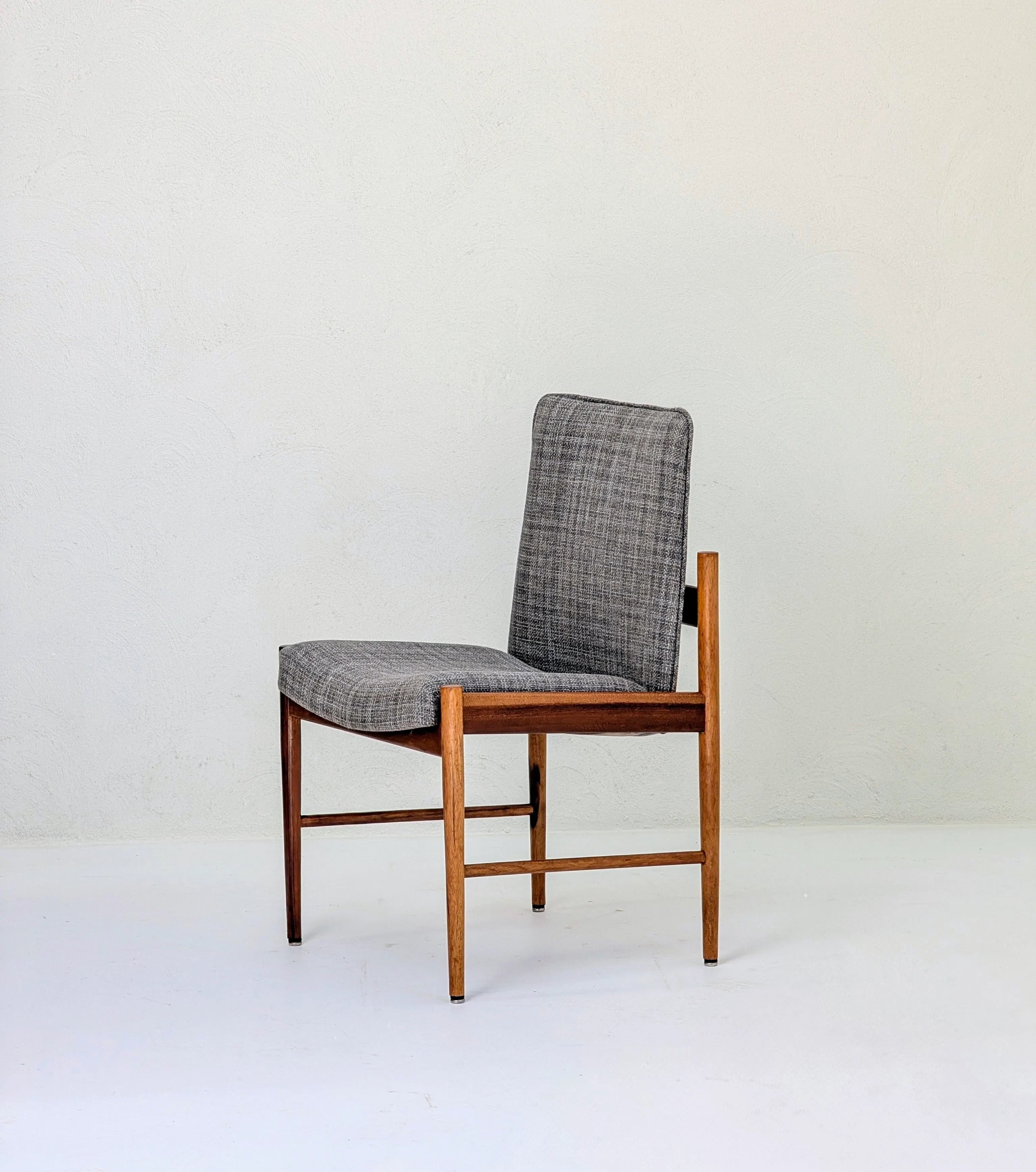 Mid-century modern wooden chair with grey upholstered seat and backrest on white floor