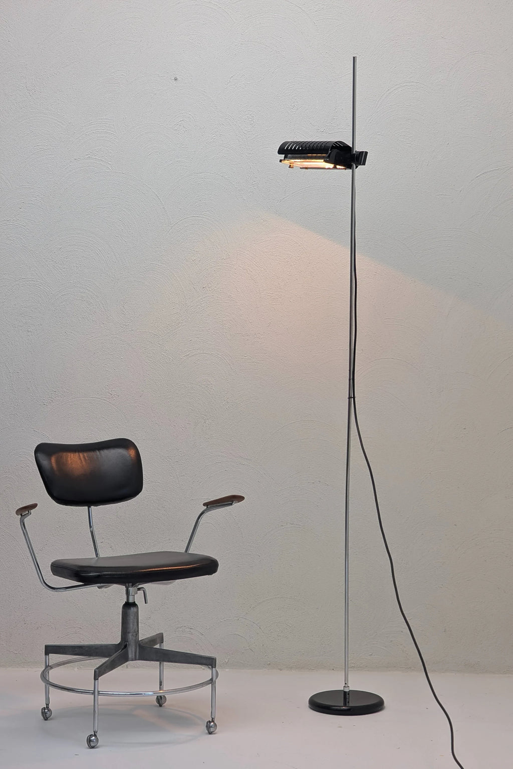 Vintage black leather swivel chair and modern floor lamp in minimalist room