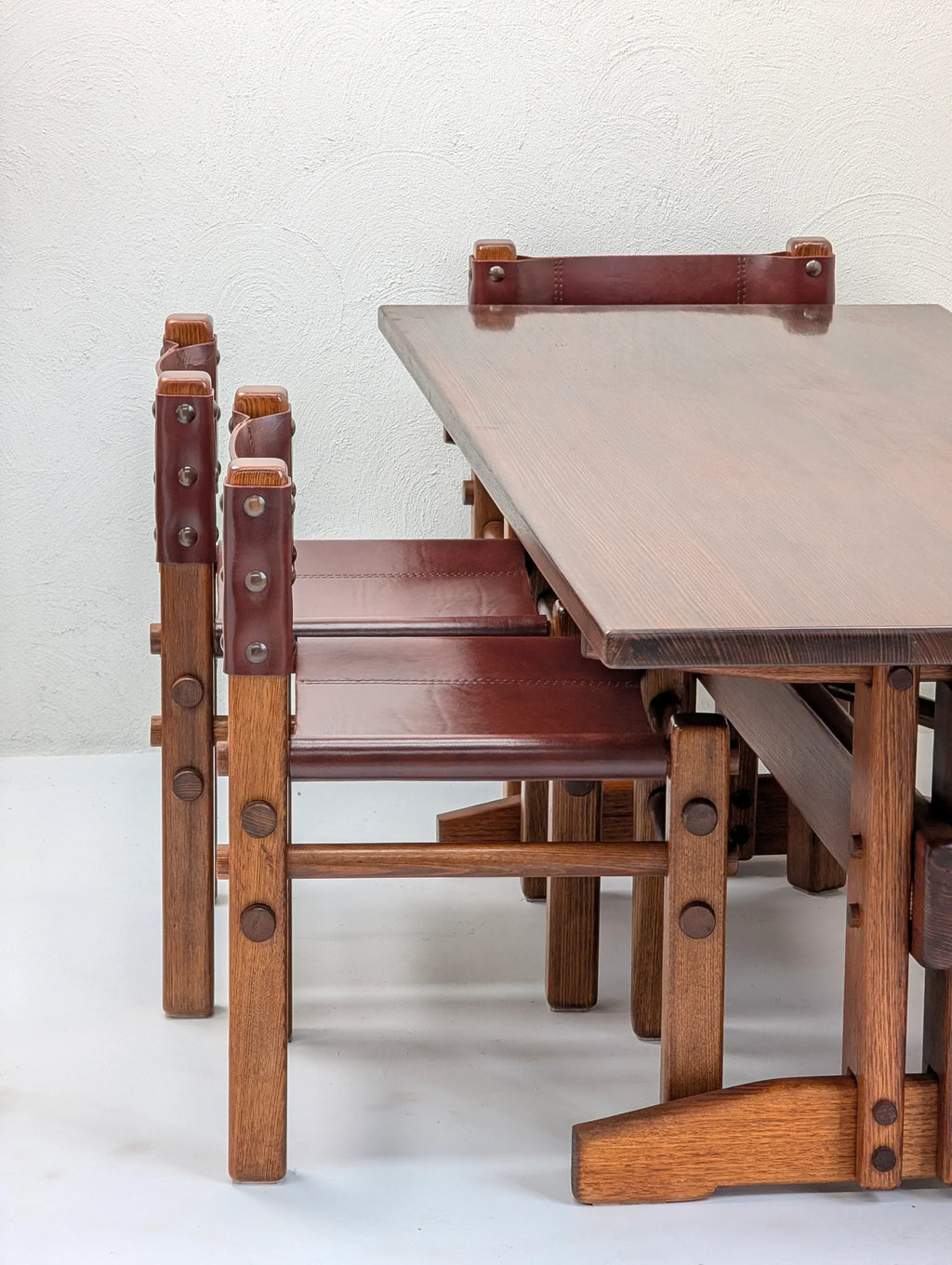 Mid-century modern wooden dining table with brown leather and wood chairs, minimalist setting