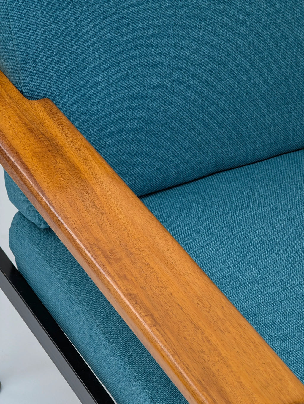 Close-up of teal fabric armchair with wooden armrest and metal frame