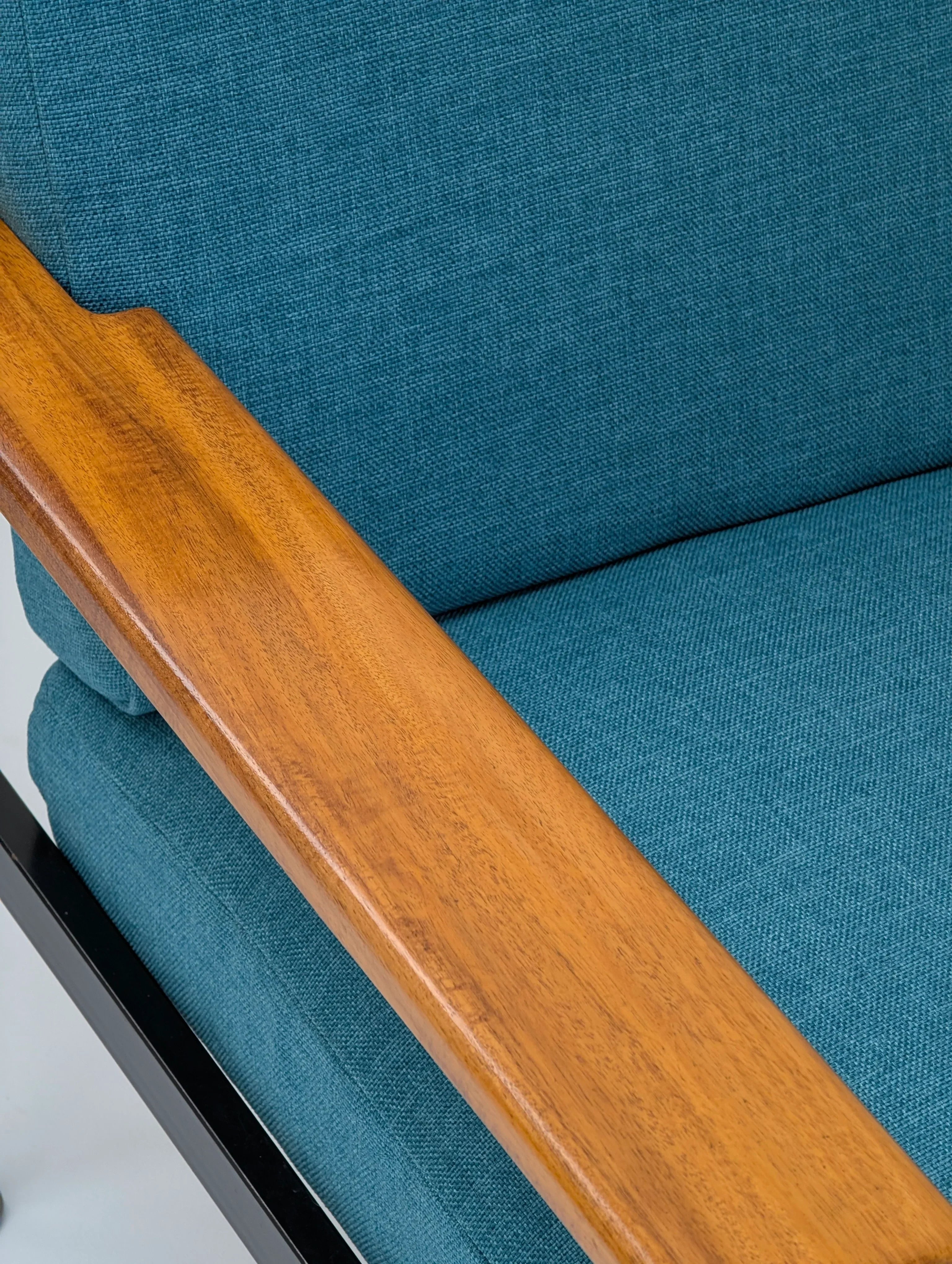 Close-up of teal fabric armchair with wooden armrest and metal frame