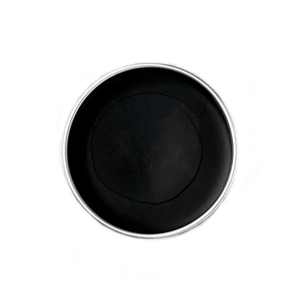 Top view of a round black balm in a tin container on a white background