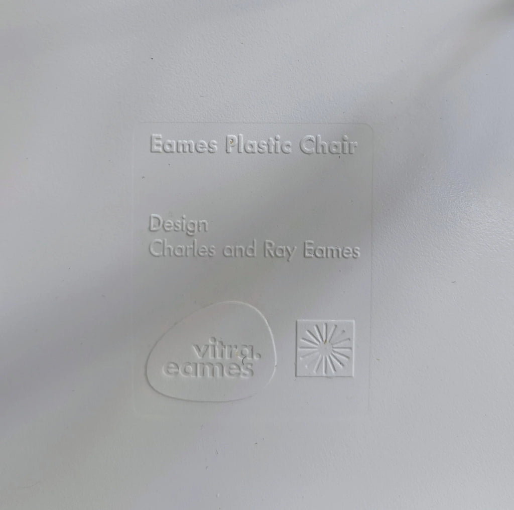 Eames Plastic Chair embossed label with Vitra eames logo and designer names on white surface