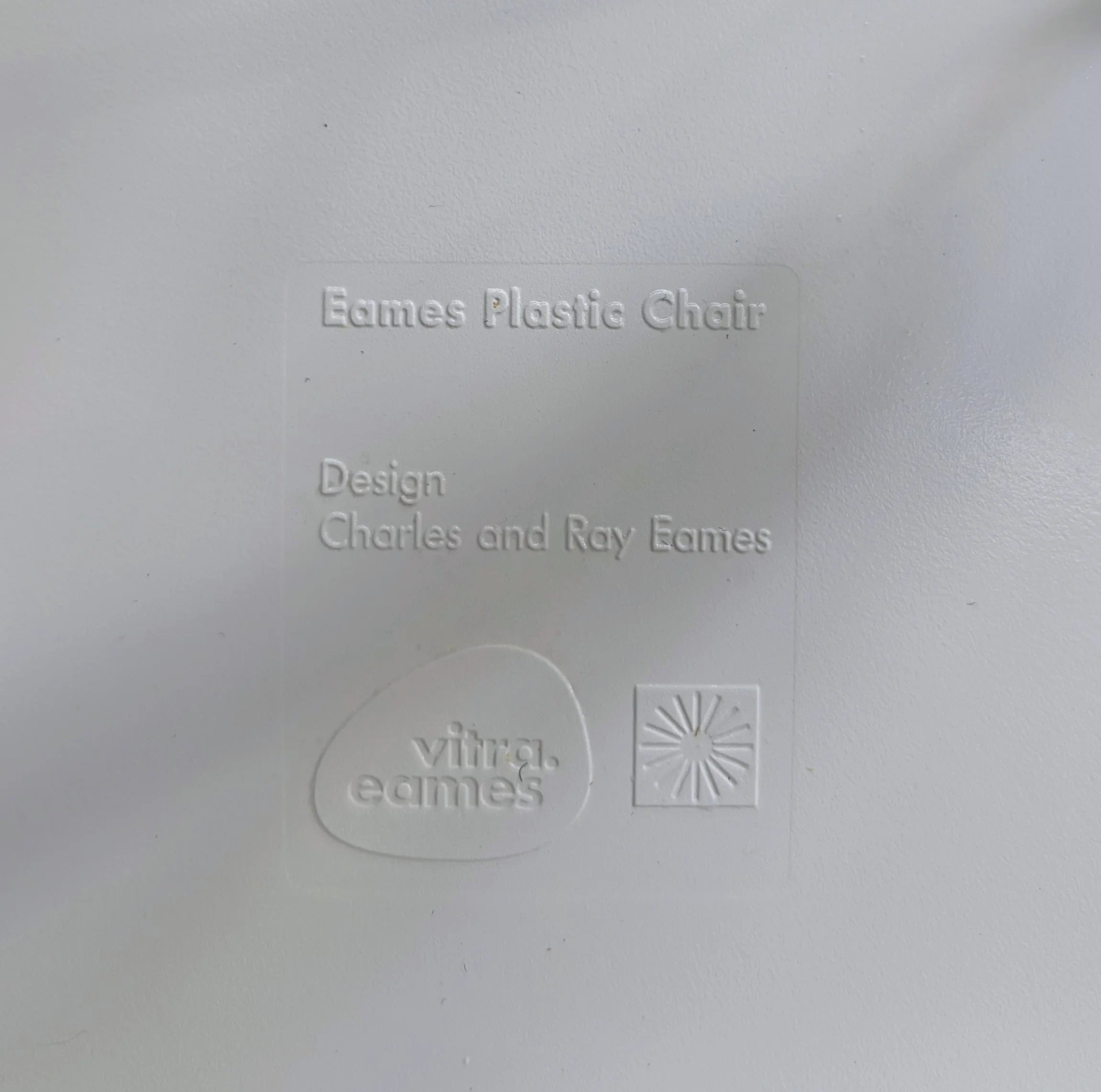 Eames Plastic Chair embossed label with Vitra eames logo and designer names on white surface