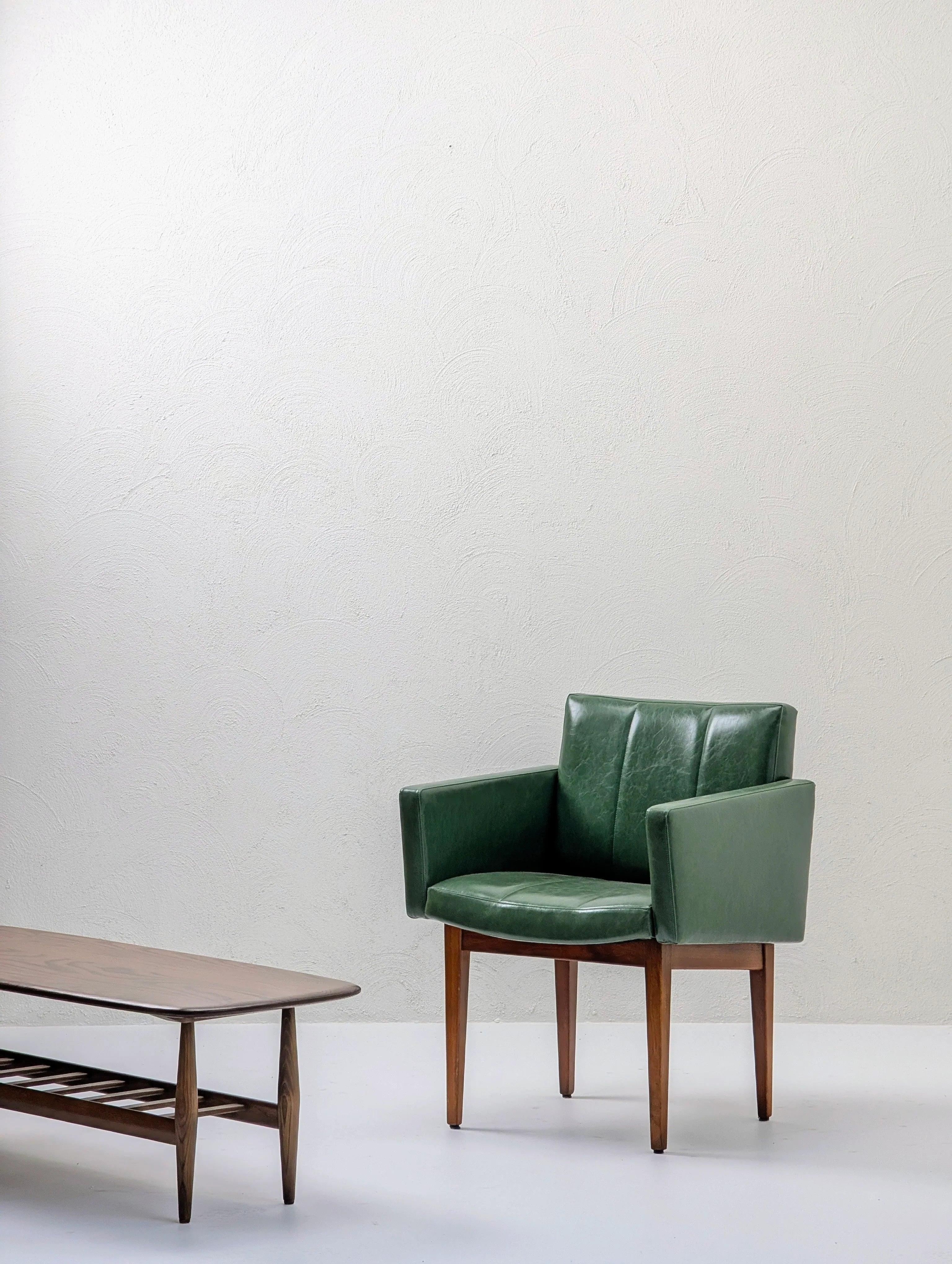 Mid-century modern green leather armchair and wooden coffee table in minimalist room