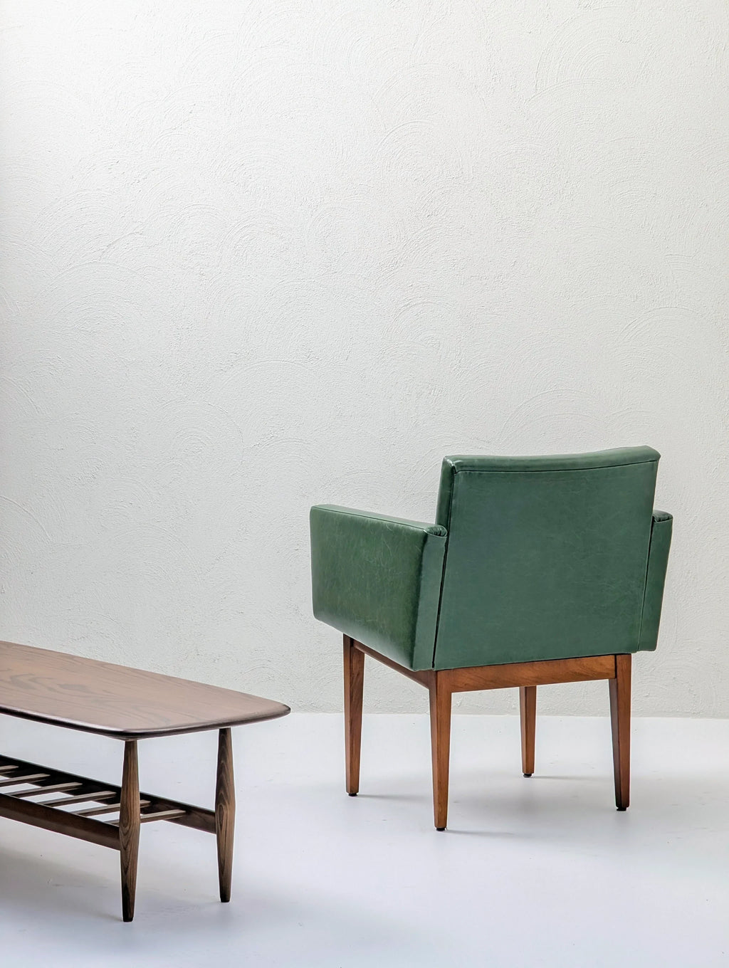Mid-century modern green armchair and wooden coffee table in minimalist room