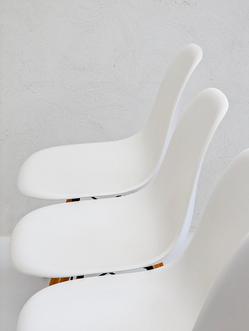 modern white minimalist chairs in a row against a light textured wall