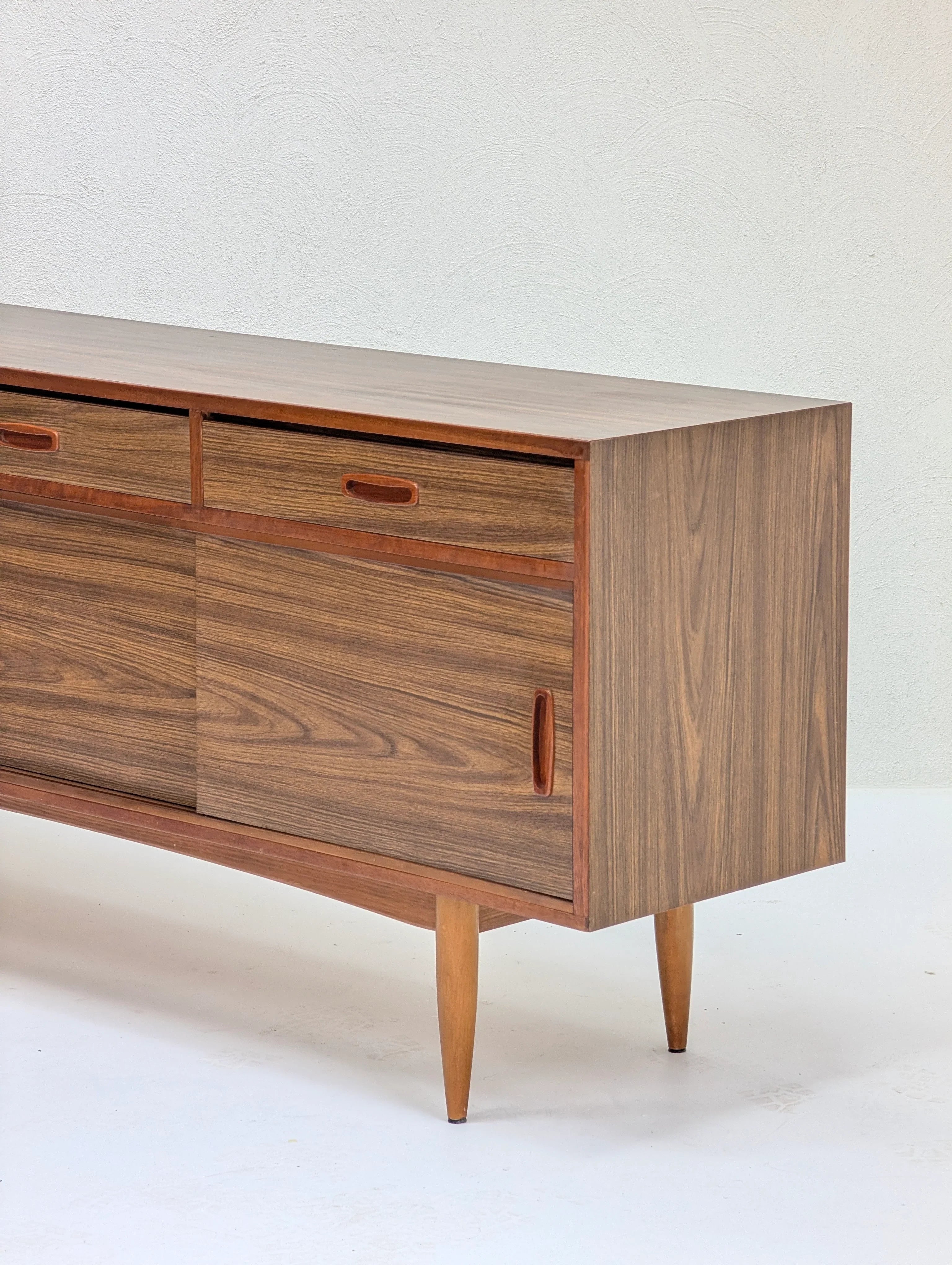 Mid-century modern wooden sideboard with two drawers and sliding doors on tapered legs