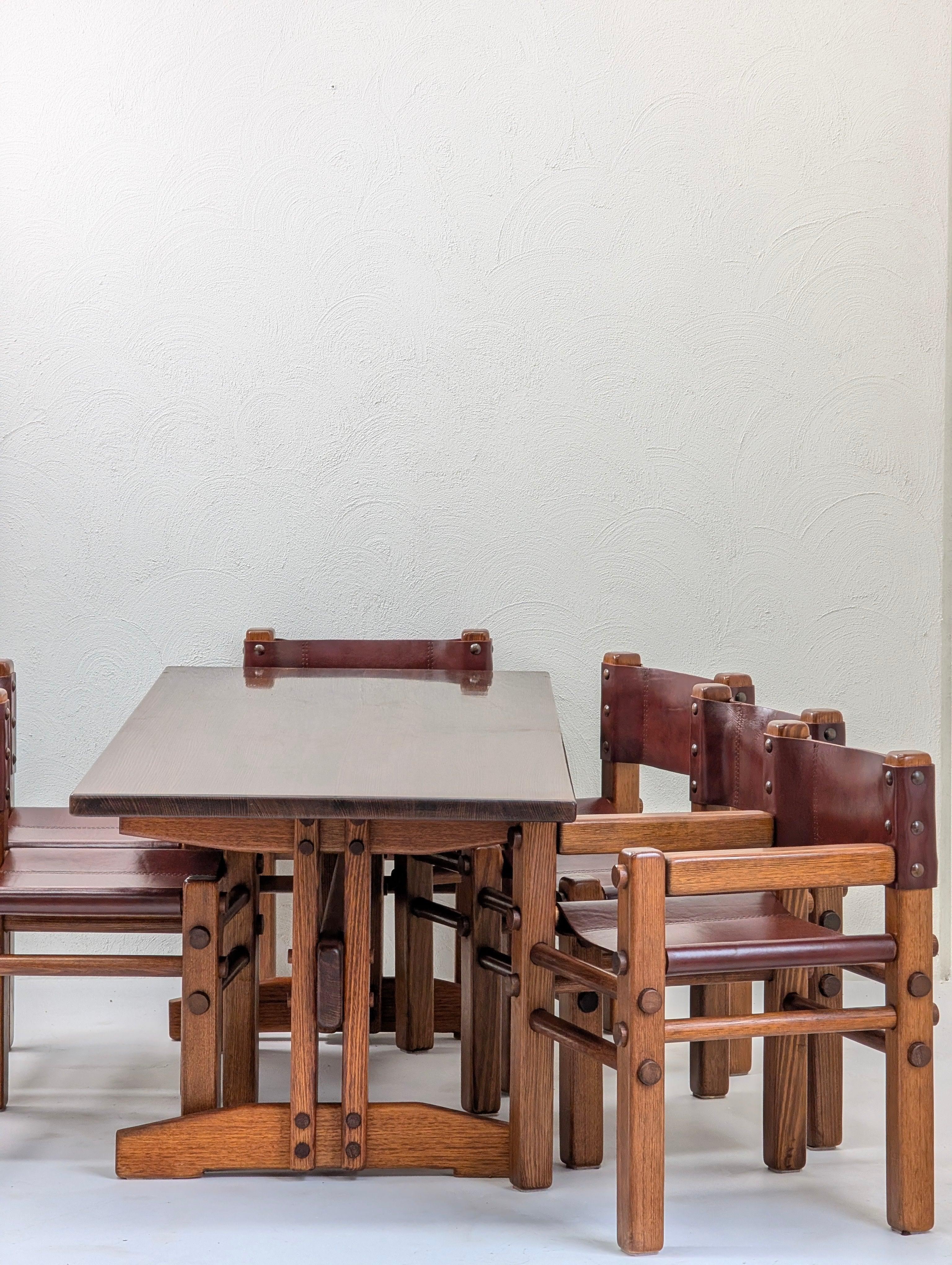 Vintage wooden dining table set with four leather and wood chairs against a white wall