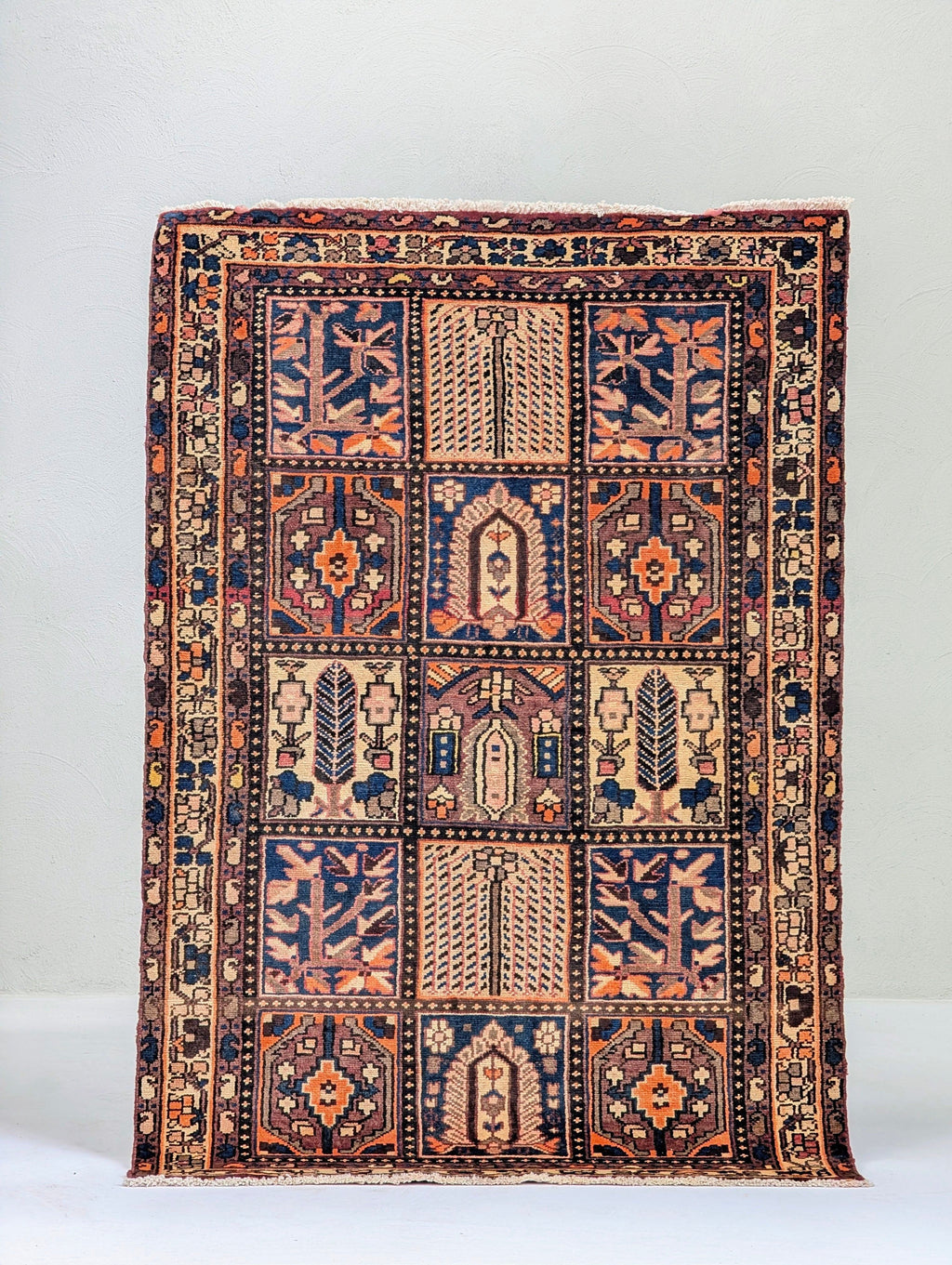 Colorful Persian rug with geometric and floral patterns in blue, orange, and beige tones