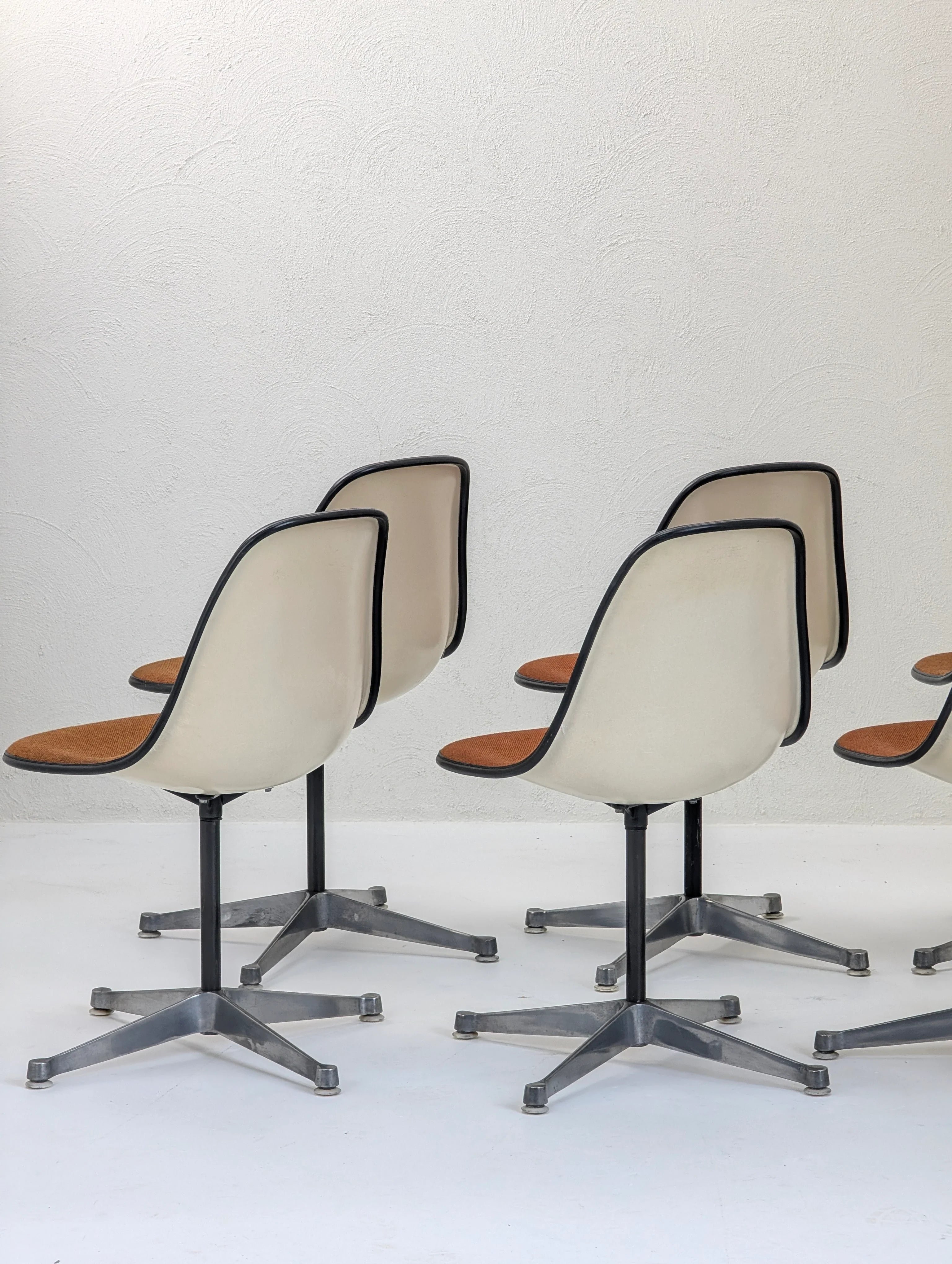 Mid-century modern office chairs with white curved backs, black trim, orange seats, and metal star-shaped bases