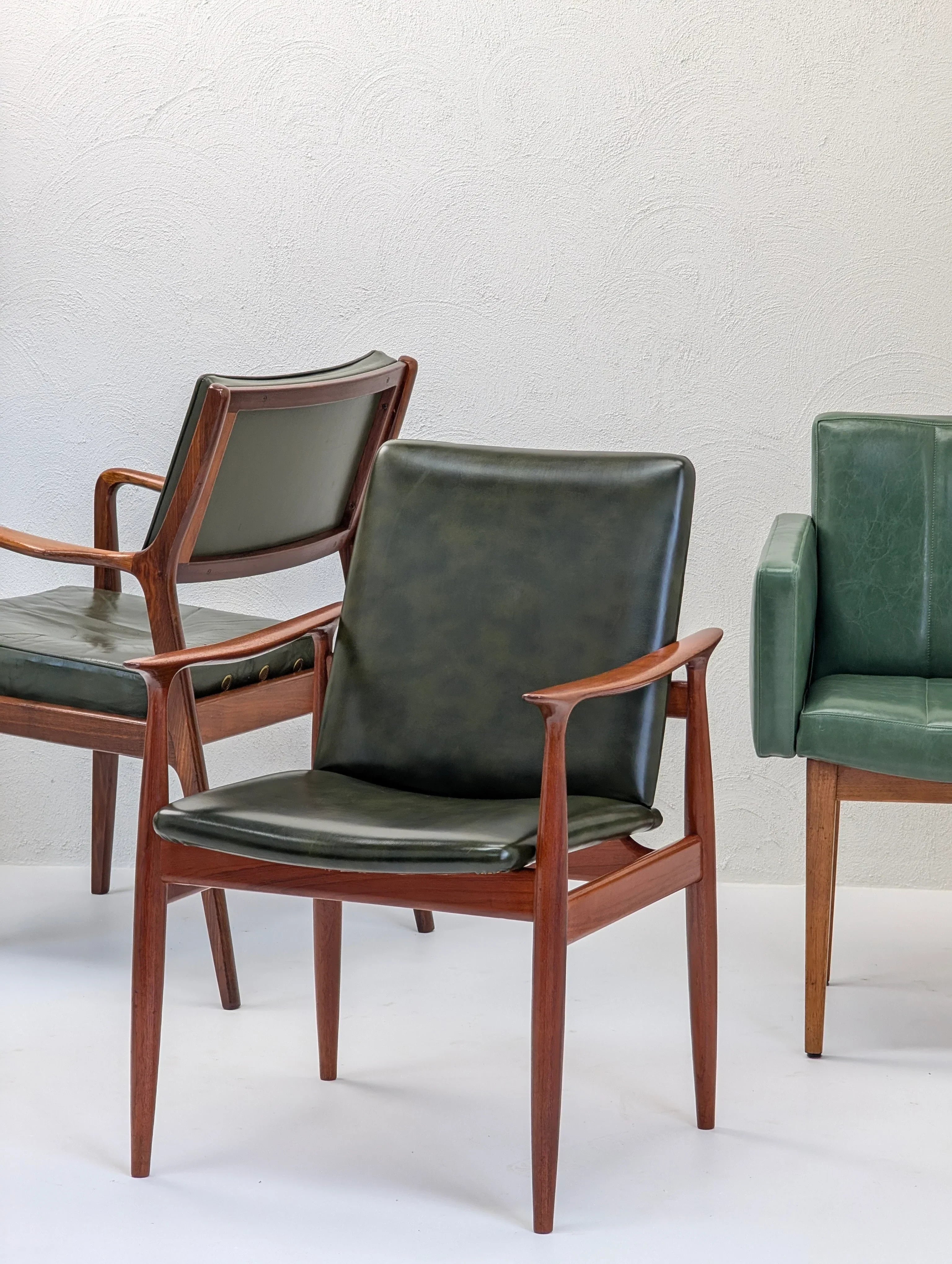 Mid-century modern green leather chairs with wooden frames on a white background