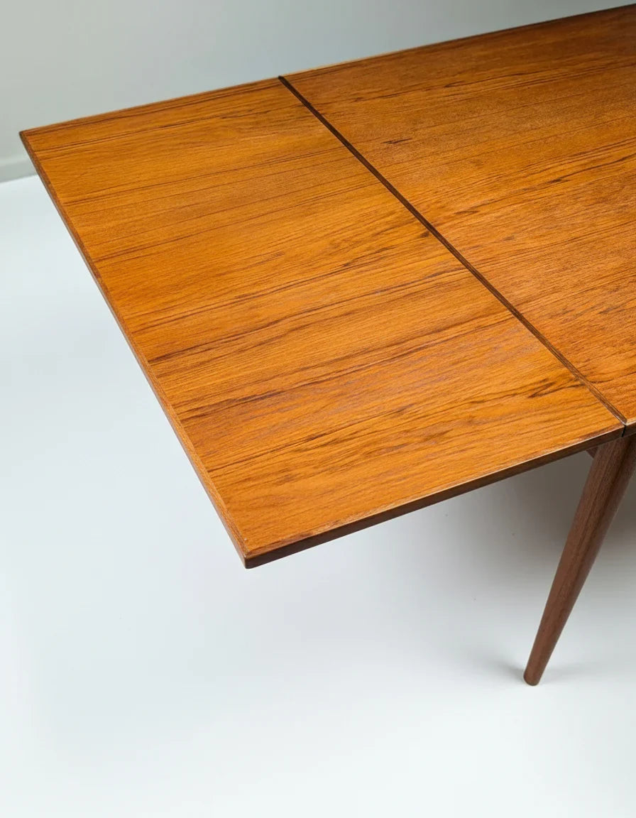 Close-up of a mid-century modern teak wood dining table corner with smooth grain and tapered leg