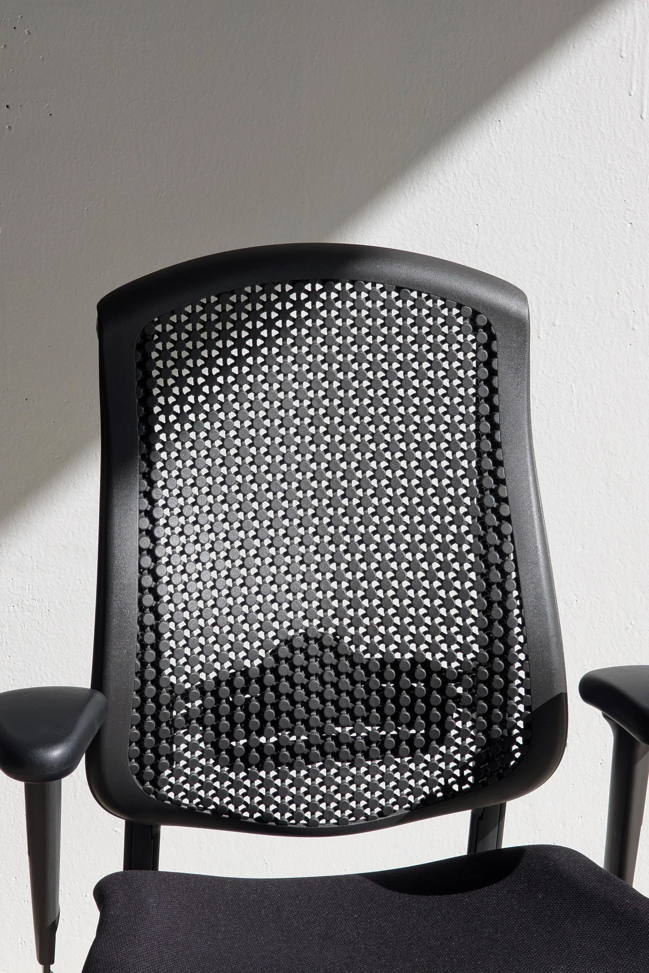 Modern black mesh office chair backrest with geometric pattern in sunlight