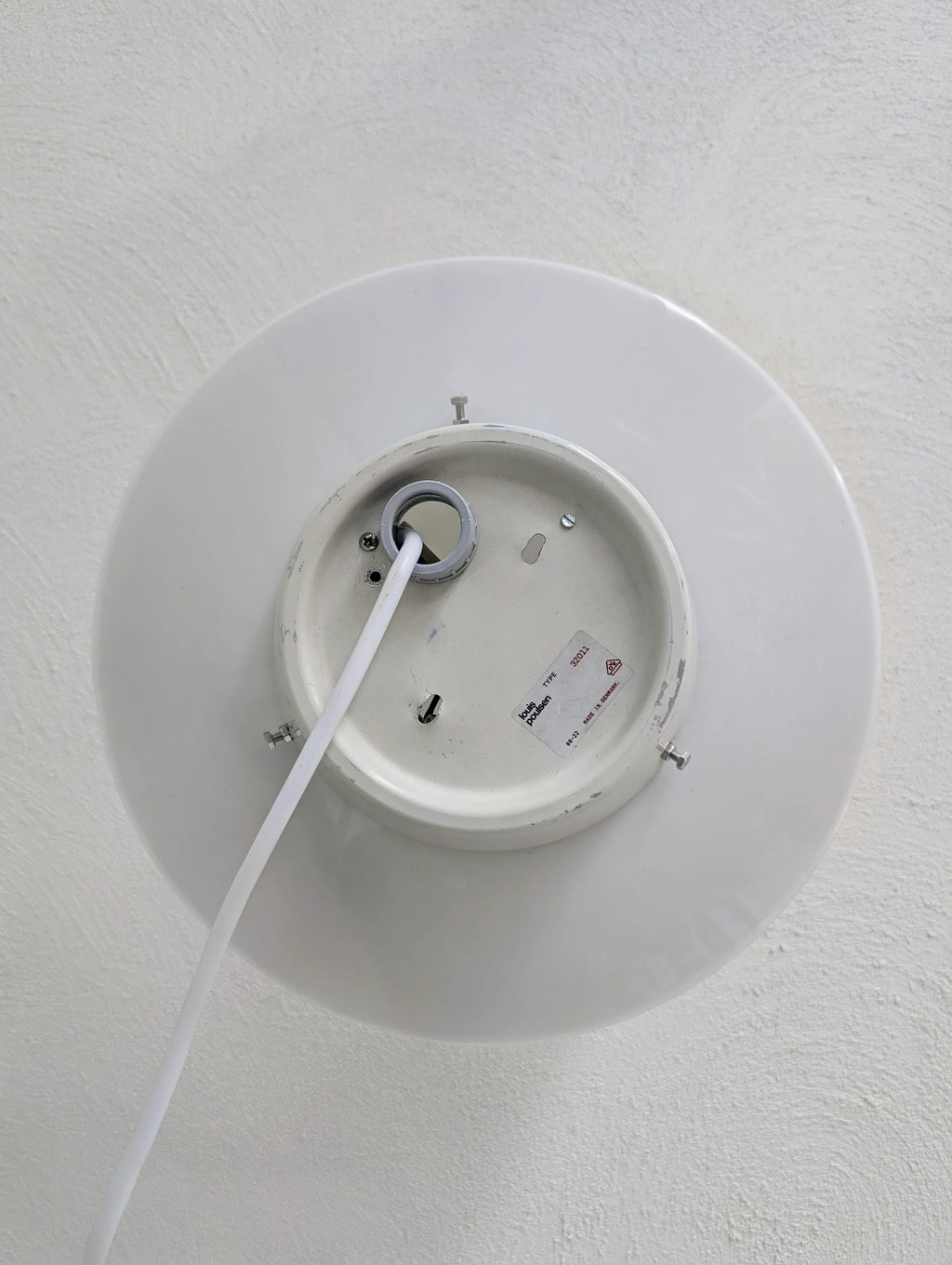 White Louis Poulsen ceiling lamp base with cable attached on textured white ceiling
