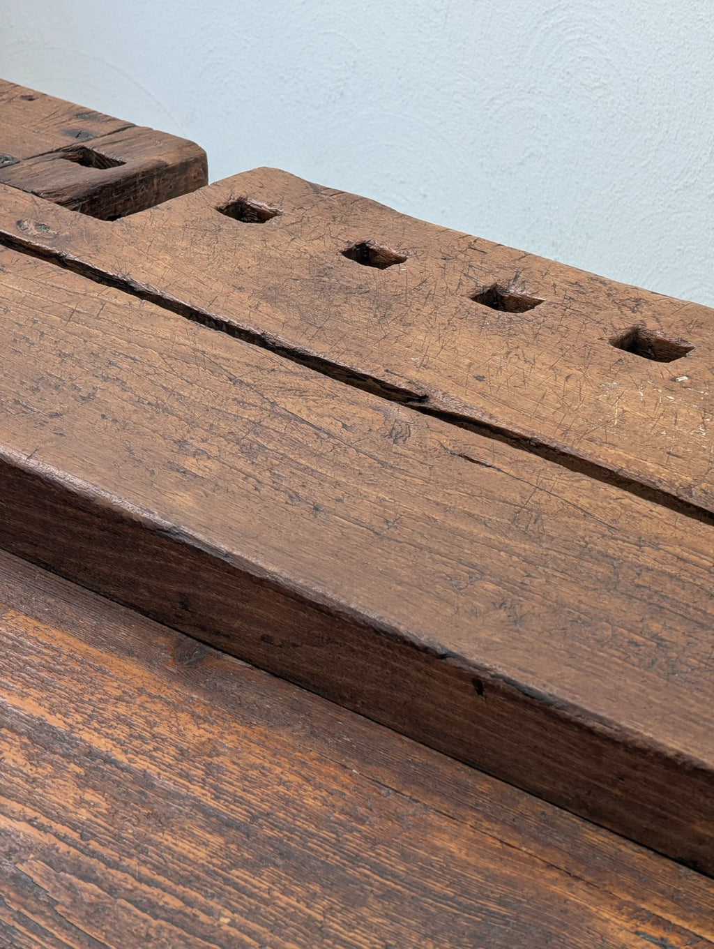 Close-up of vintage wooden workbench surface with square holes and textured grain