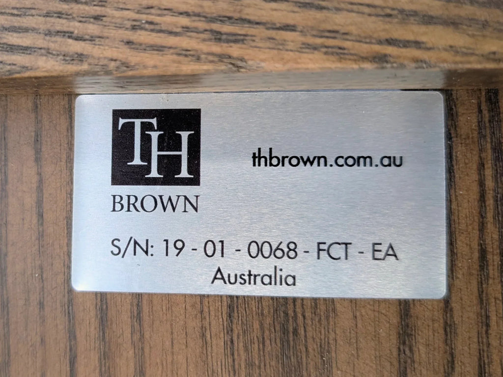 TH Brown metal label with website and serial number on wood furniture surface, Australia