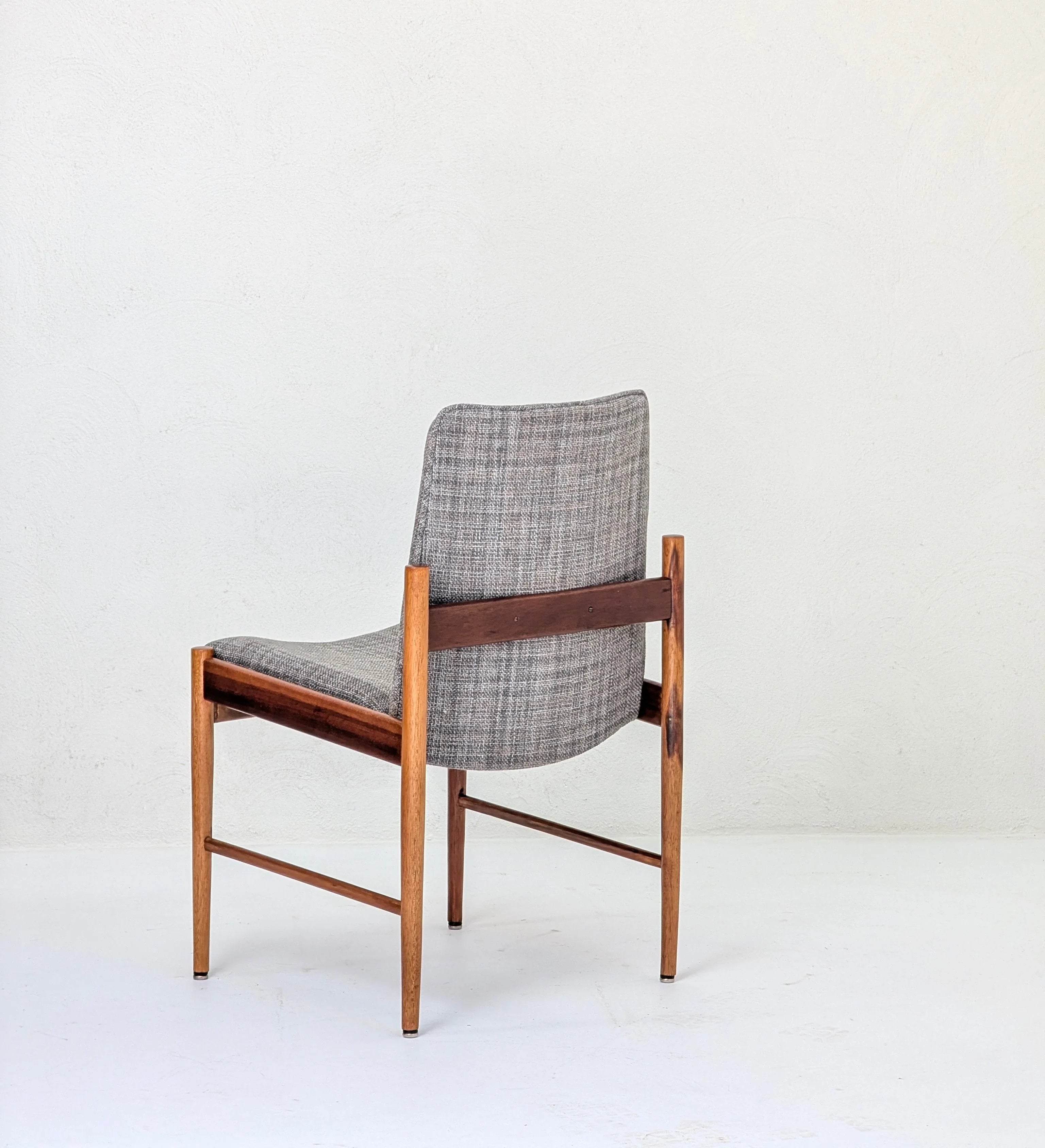 Mid-century modern wooden chair with grey plaid upholstered seat and backrest against white wall