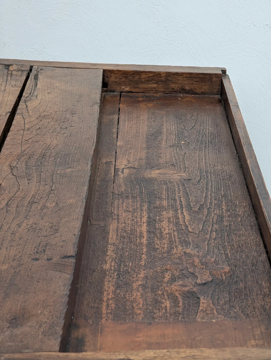 Rustic reclaimed wood tabletop with natural grain against a white wall background