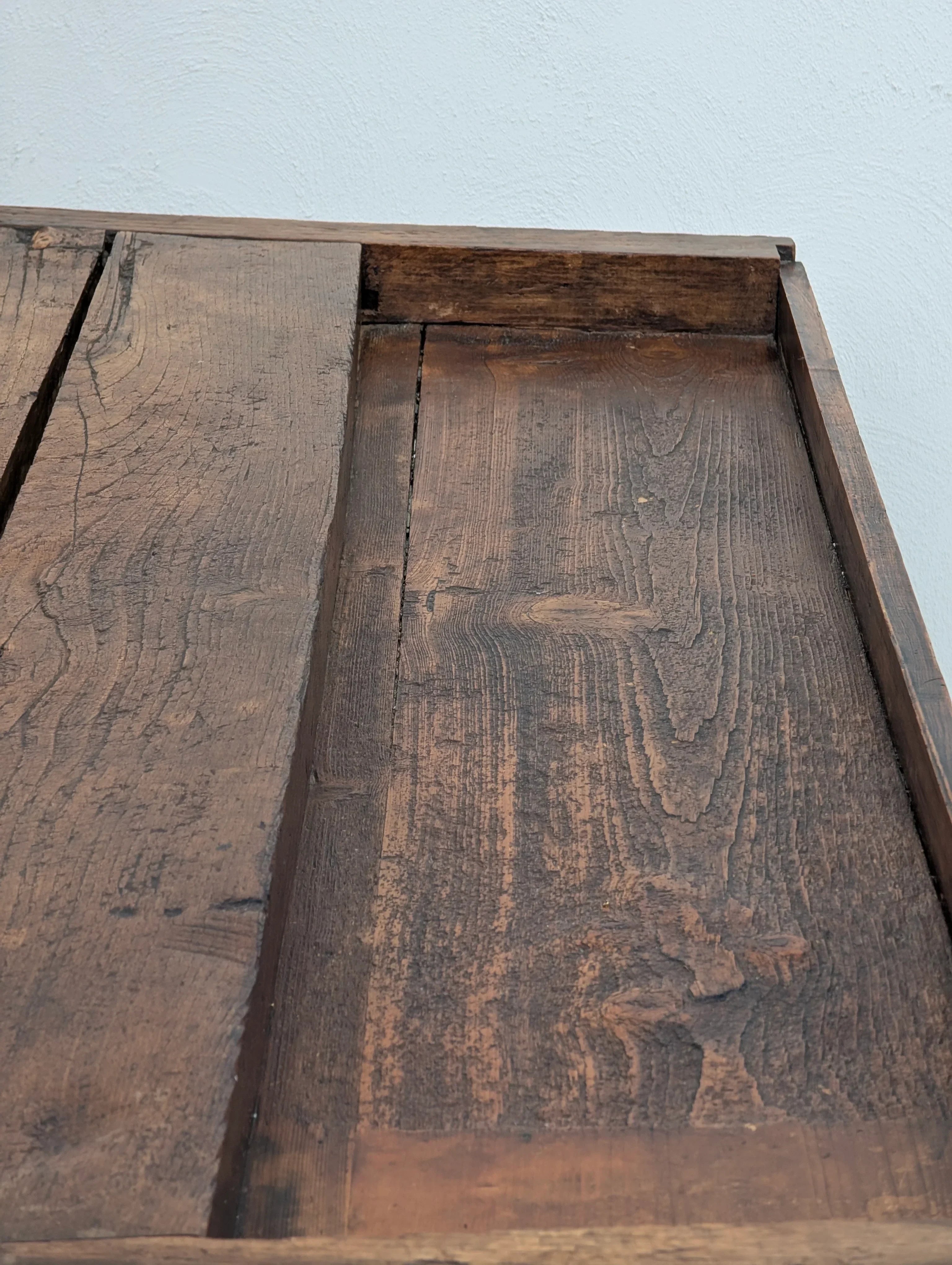 Rustic reclaimed wood tabletop with natural grain against a white wall background