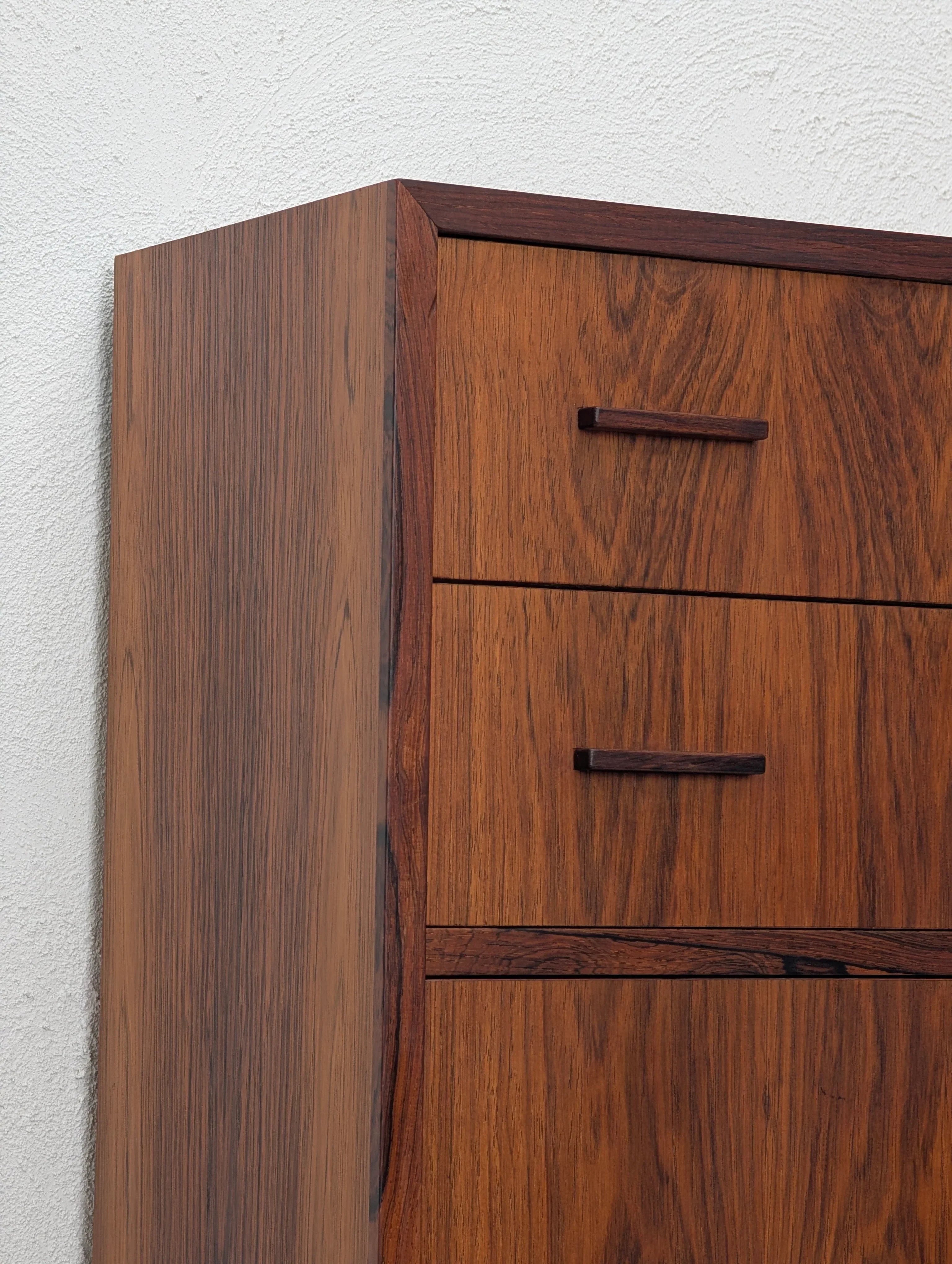 Mid-century modern wooden dresser with dark wood grain and minimalist handles against white wall