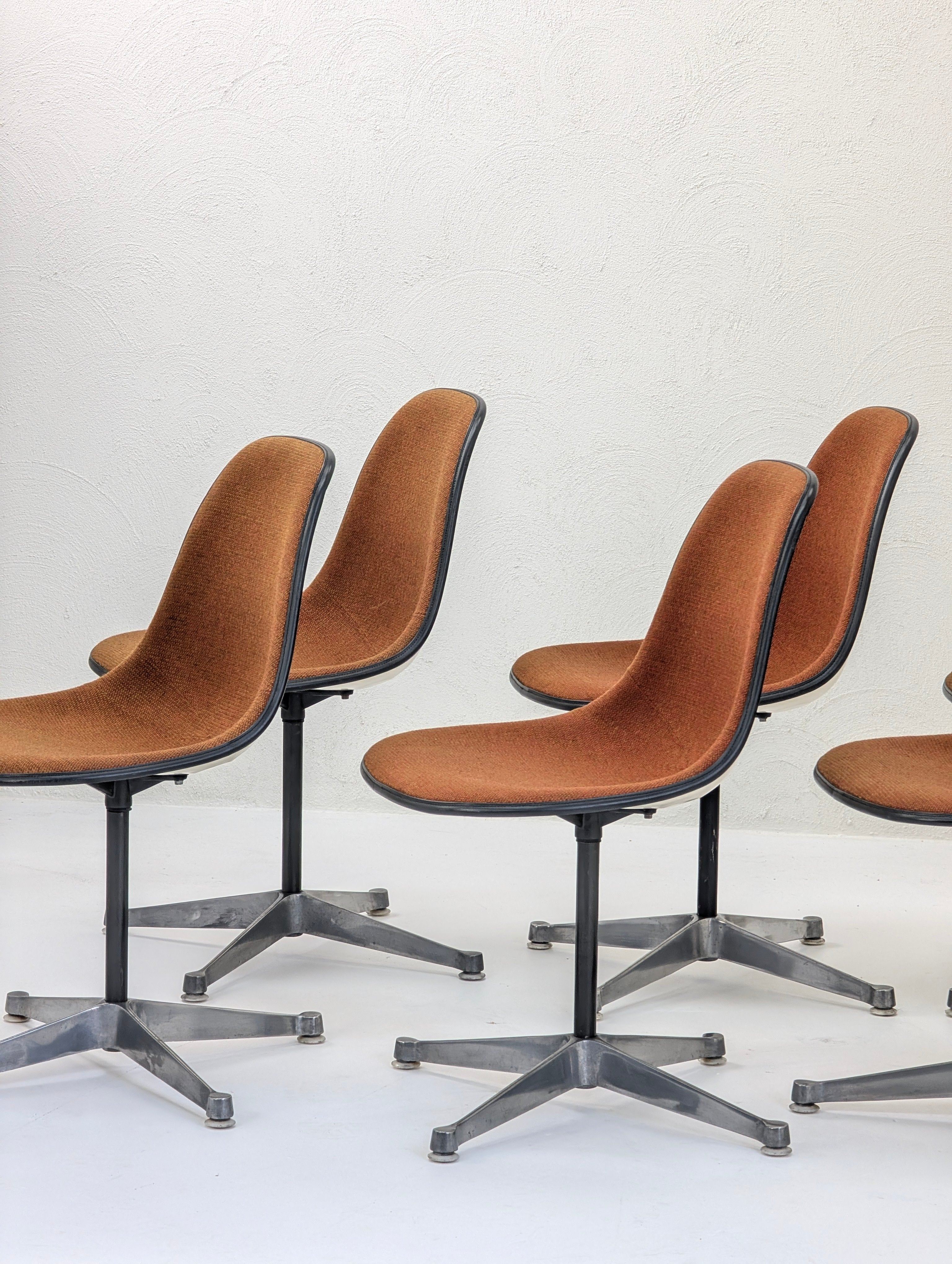 Set of five mid-century modern brown swivel chairs with metal star-shaped bases on white floor