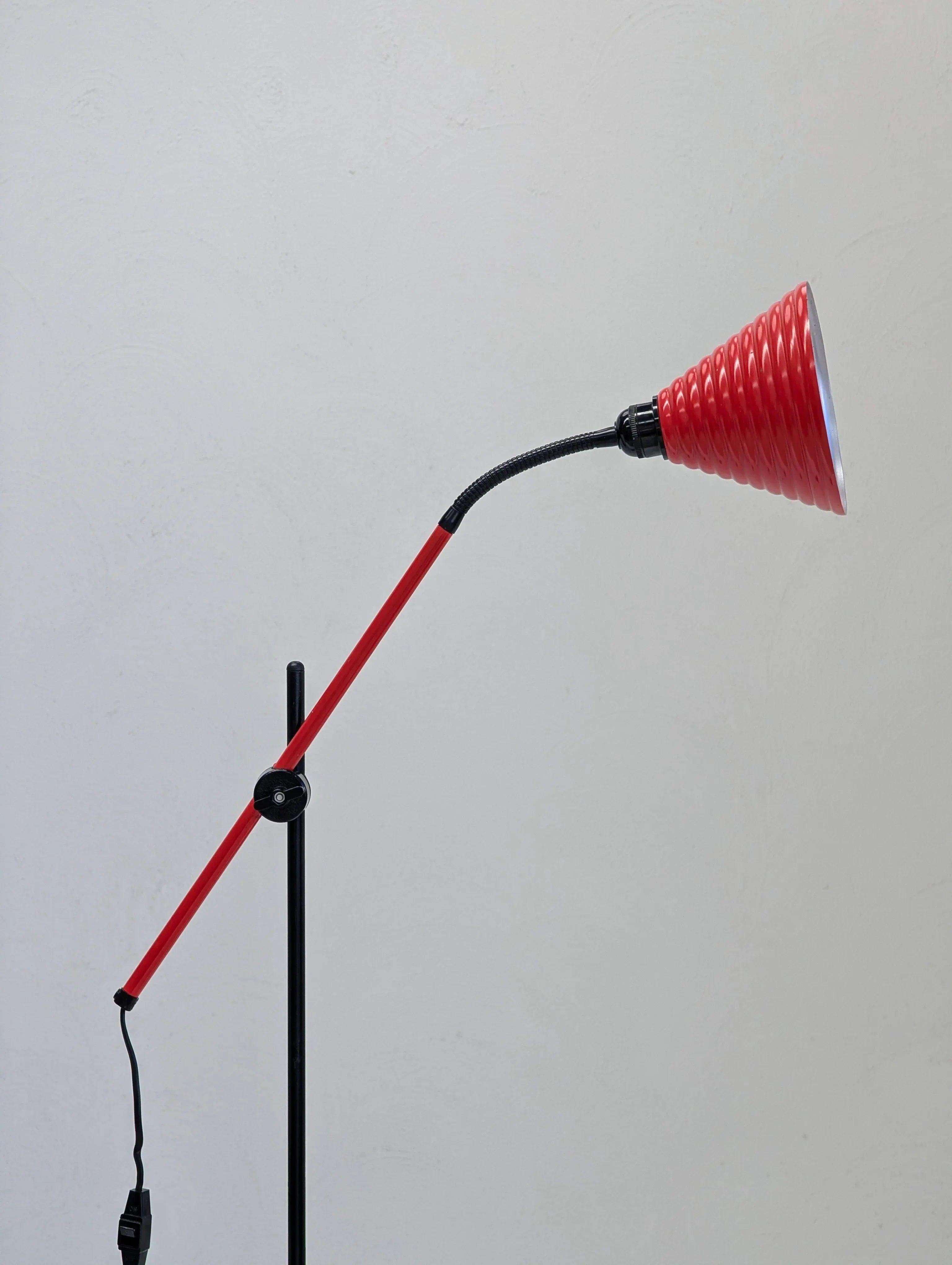 Red modern adjustable desk lamp with textured shade against a plain light gray wall