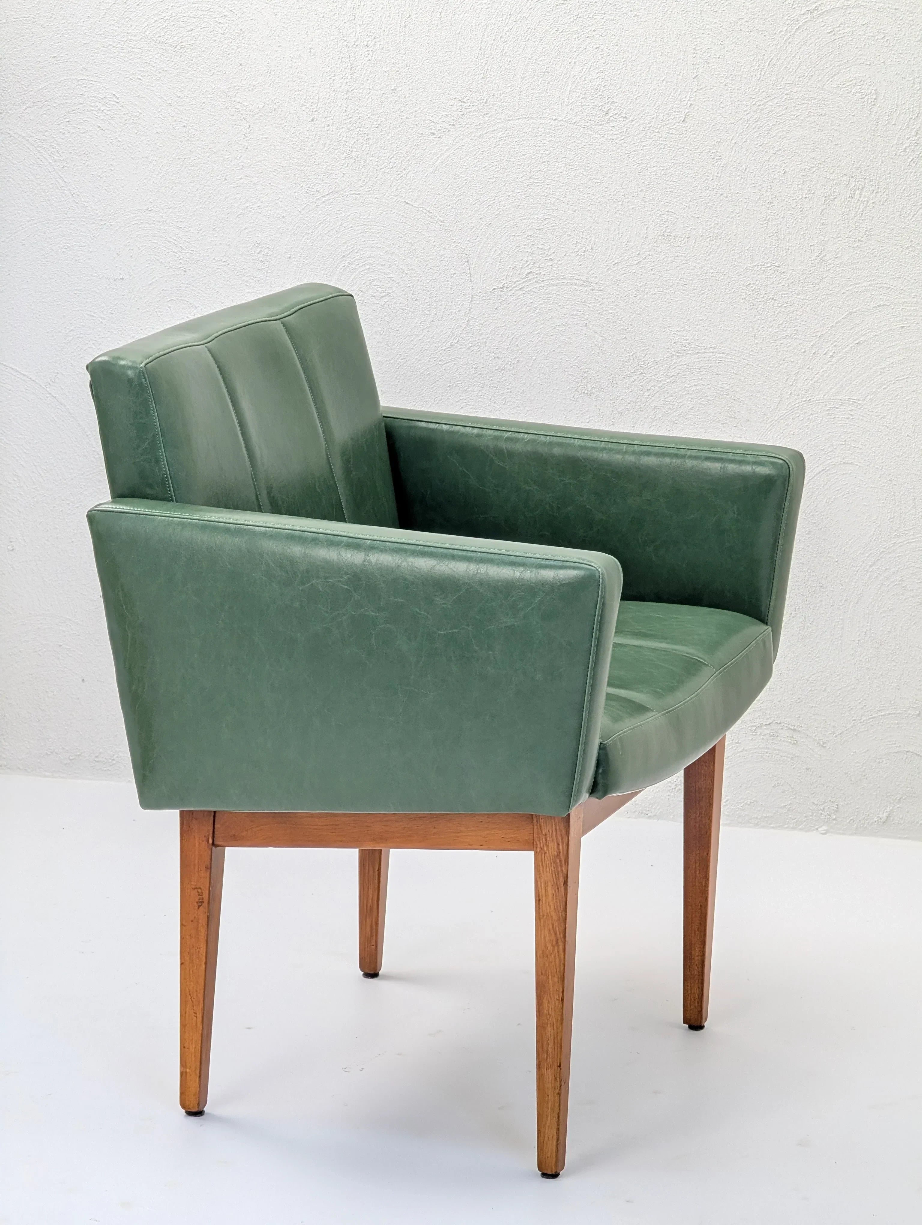 Green mid-century modern armchair with wooden legs in a minimal white room