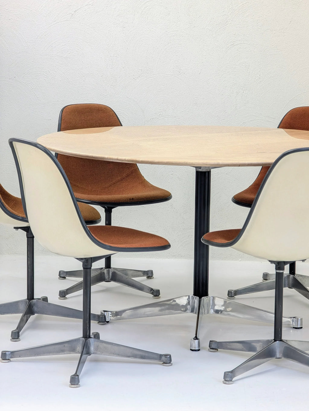 Mid-century modern round table with four brown and cream swivel chairs on metal bases