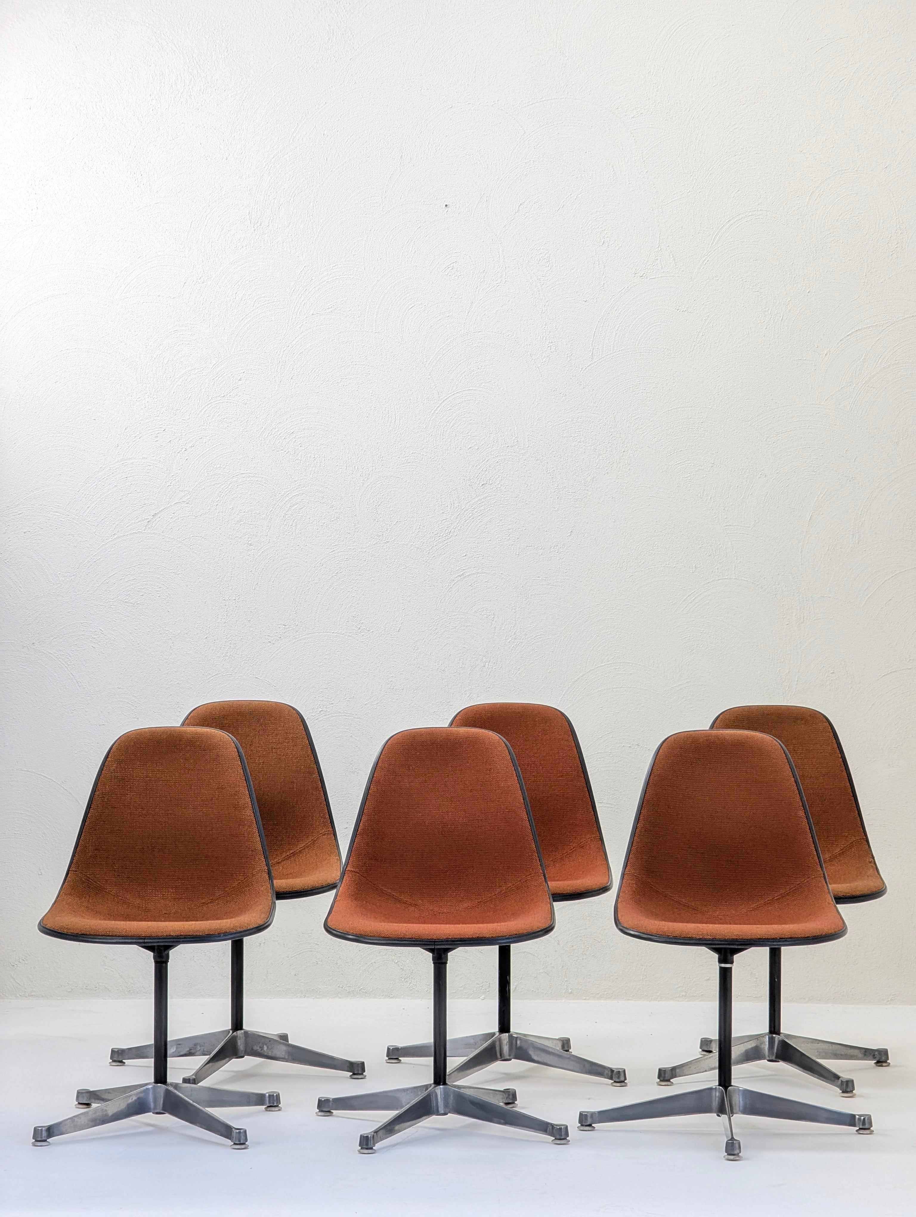 Set of six vintage brown swivel office chairs with metal bases against a white textured wall