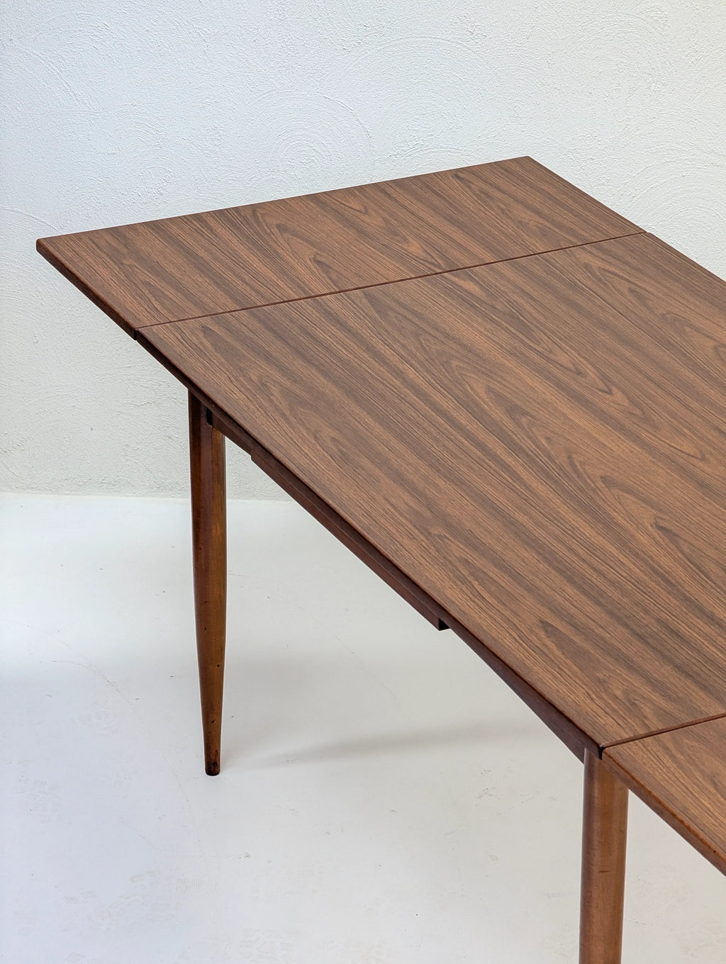 Mid-century modern wooden dining table with tapered legs and wood grain surface