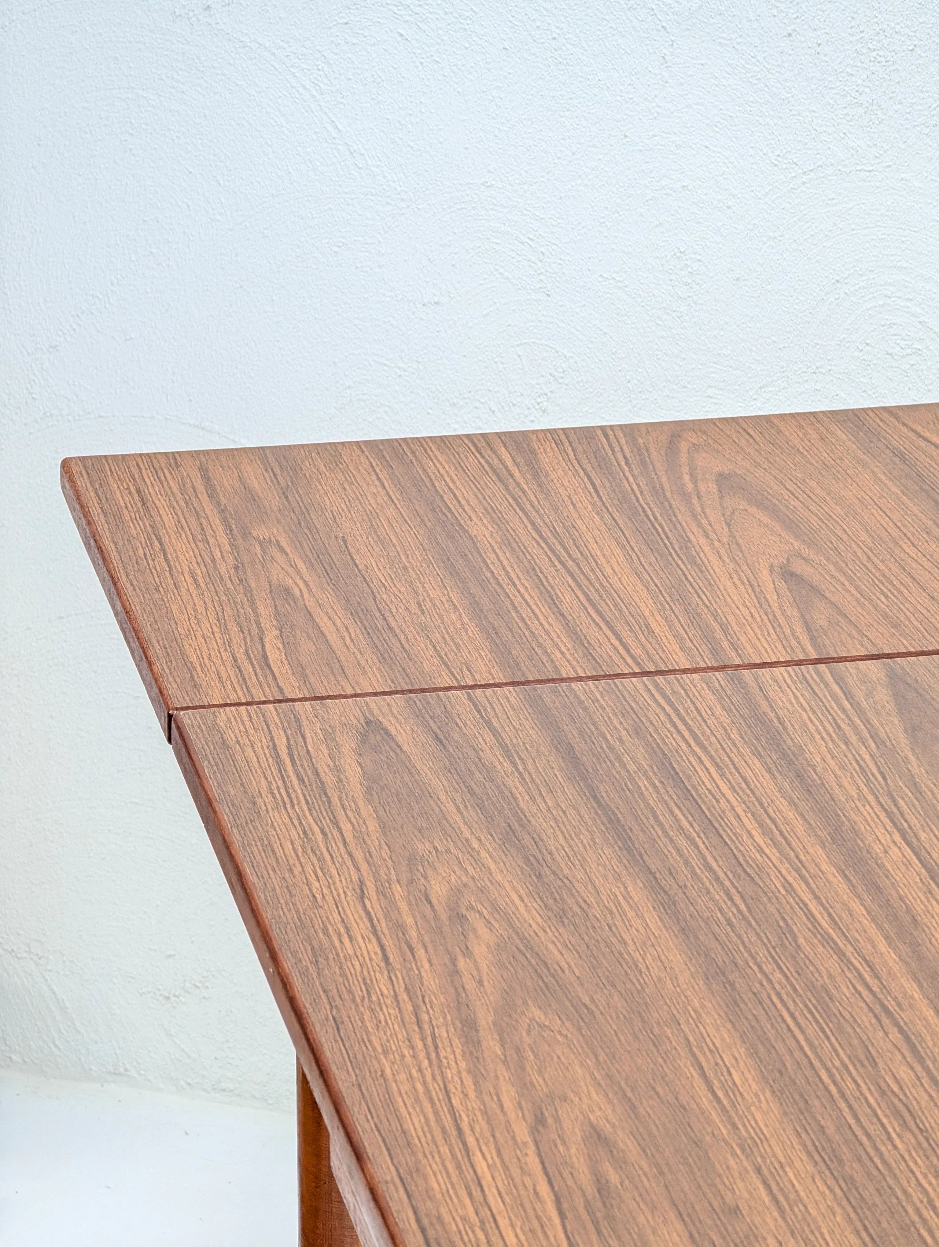 Close-up of corner of wooden table with natural wood grain against white textured wall