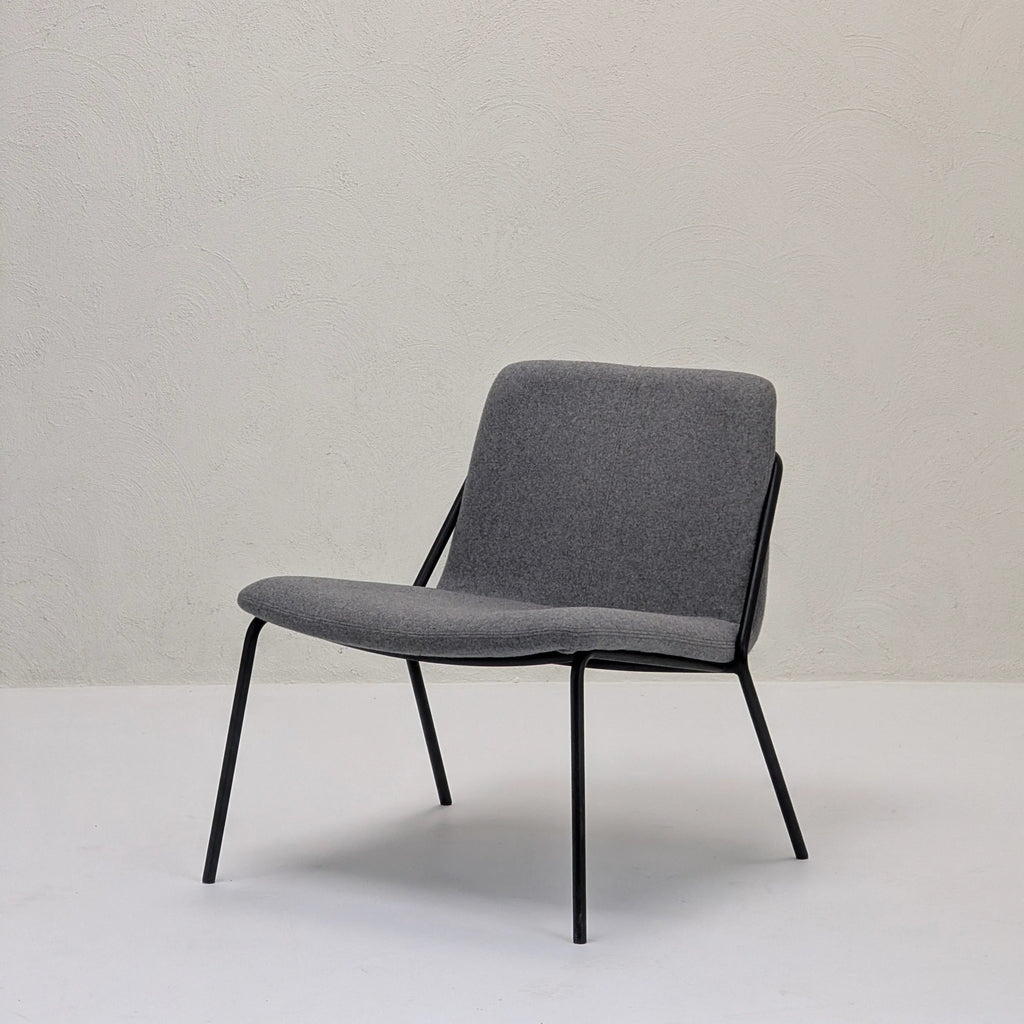 Modern lounge chair with gray fabric seat and black metal frame in minimalist room