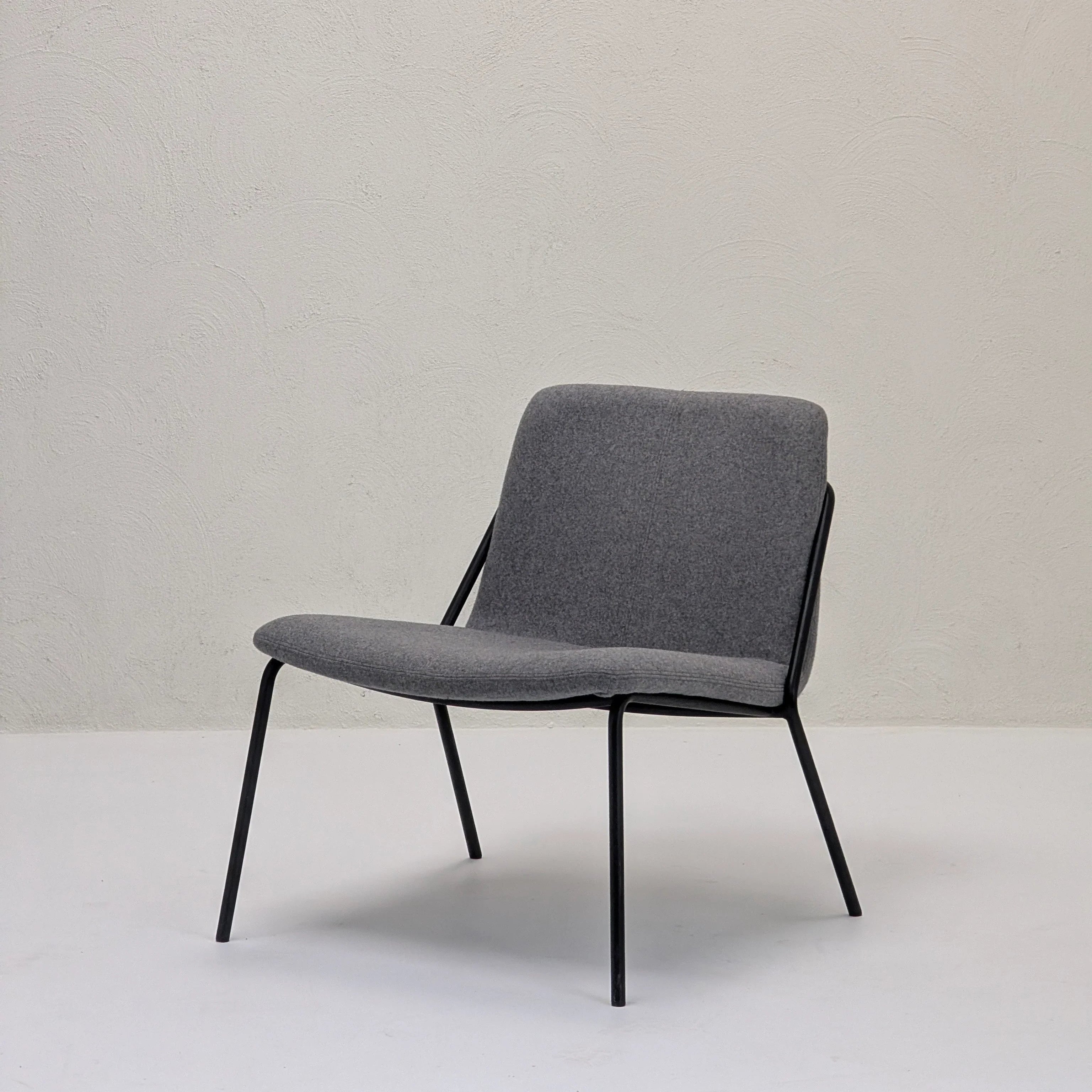 Modern lounge chair with gray fabric seat and black metal frame in minimalist room