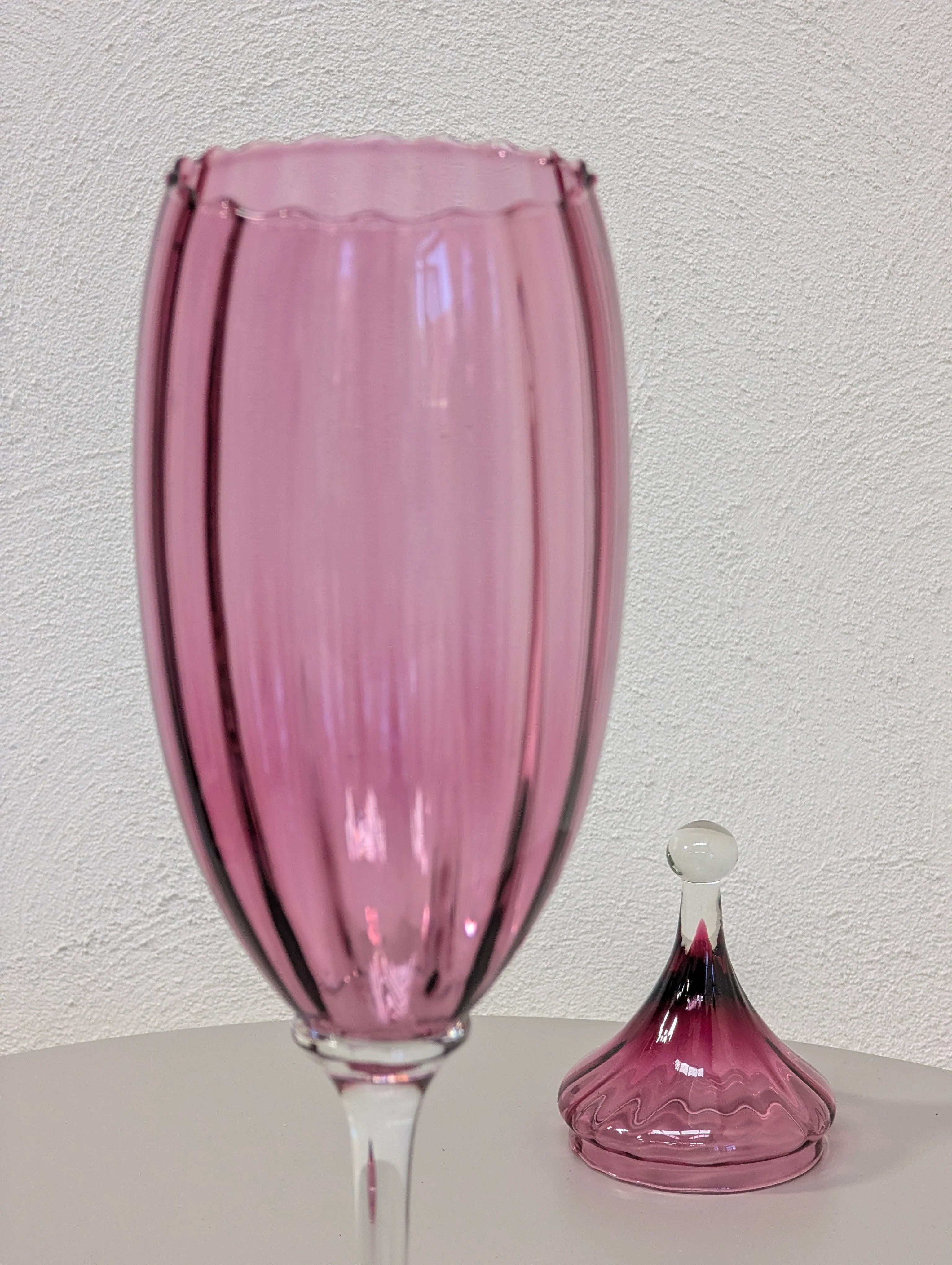 Close-up of a pink ribbed glass goblet with matching pink glass lid on white table