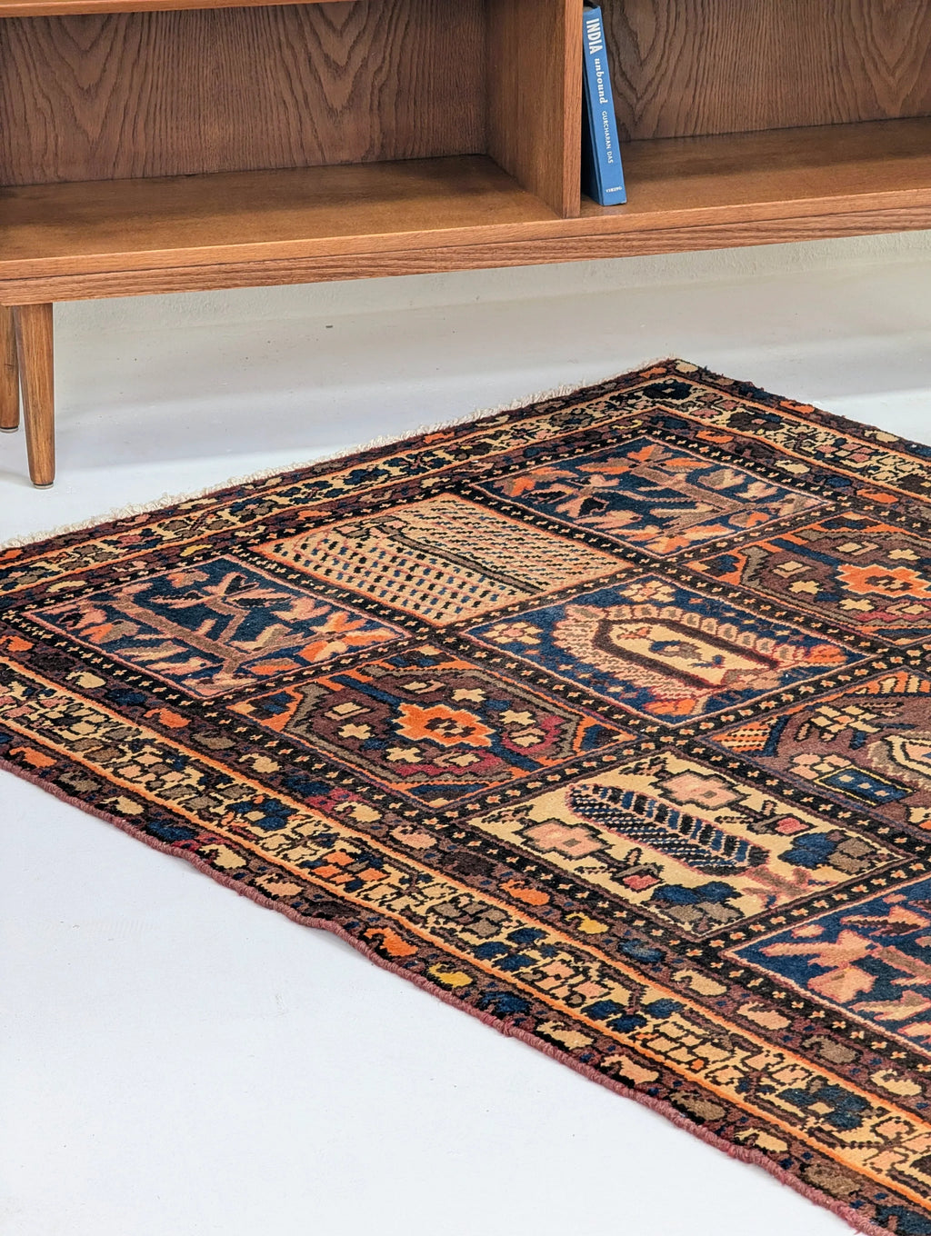 Colorful vintage oriental rug with geometric patterns on white floor under wooden furniture