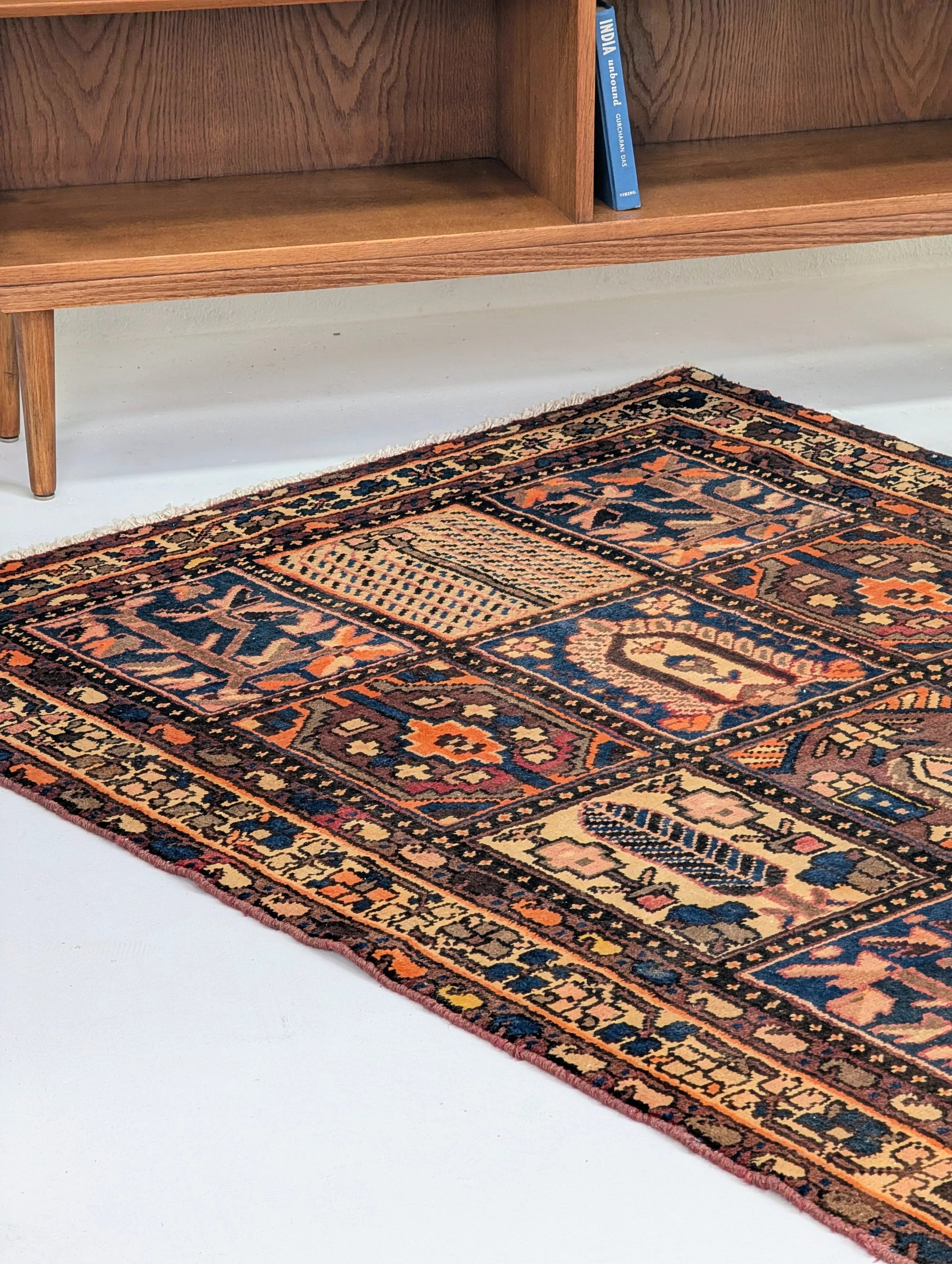 Colorful vintage oriental rug with geometric patterns on white floor under wooden furniture