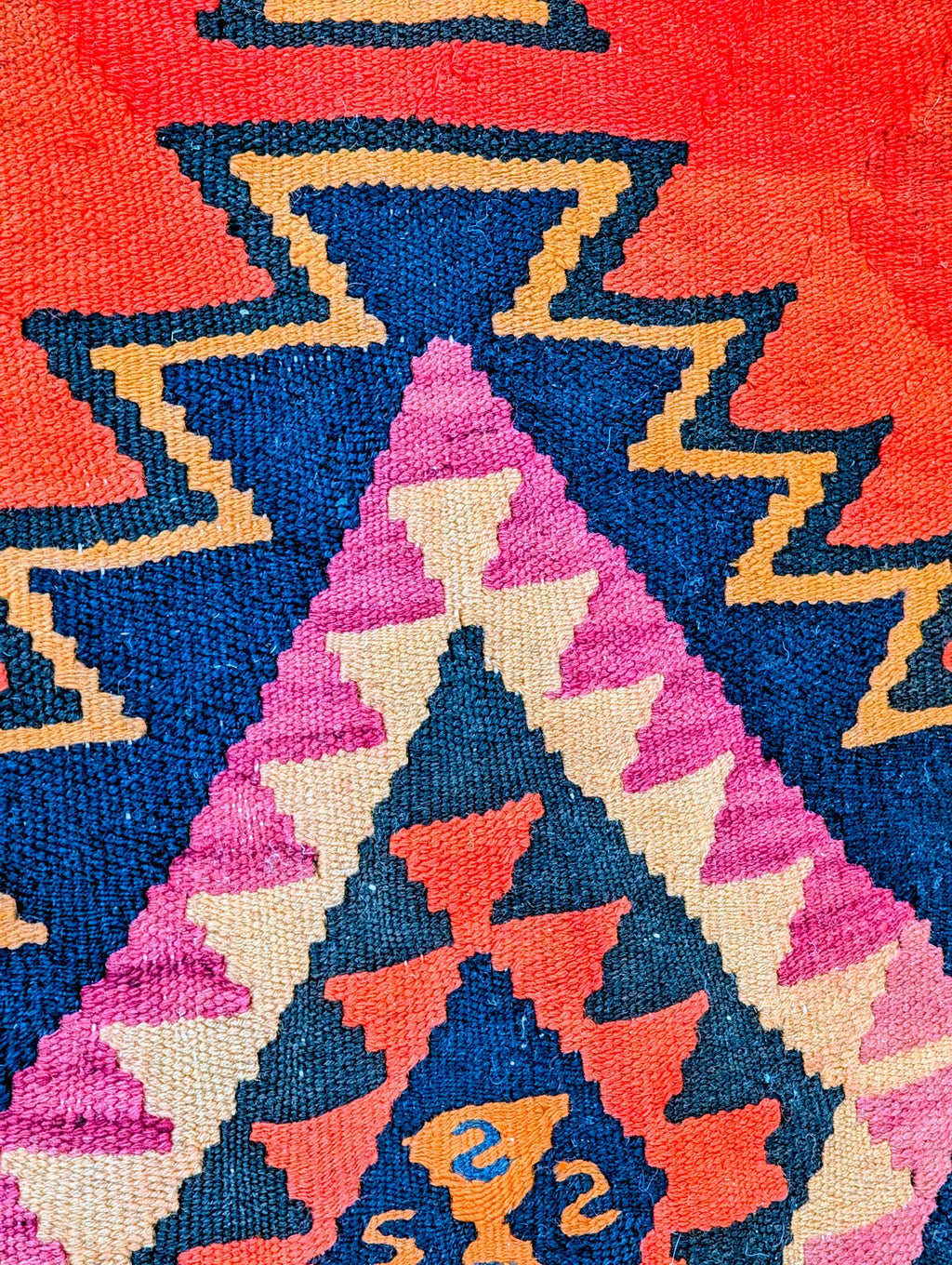 Colorful geometric pattern on a woven textile rug with zigzag designs in red, blue, pink, beige