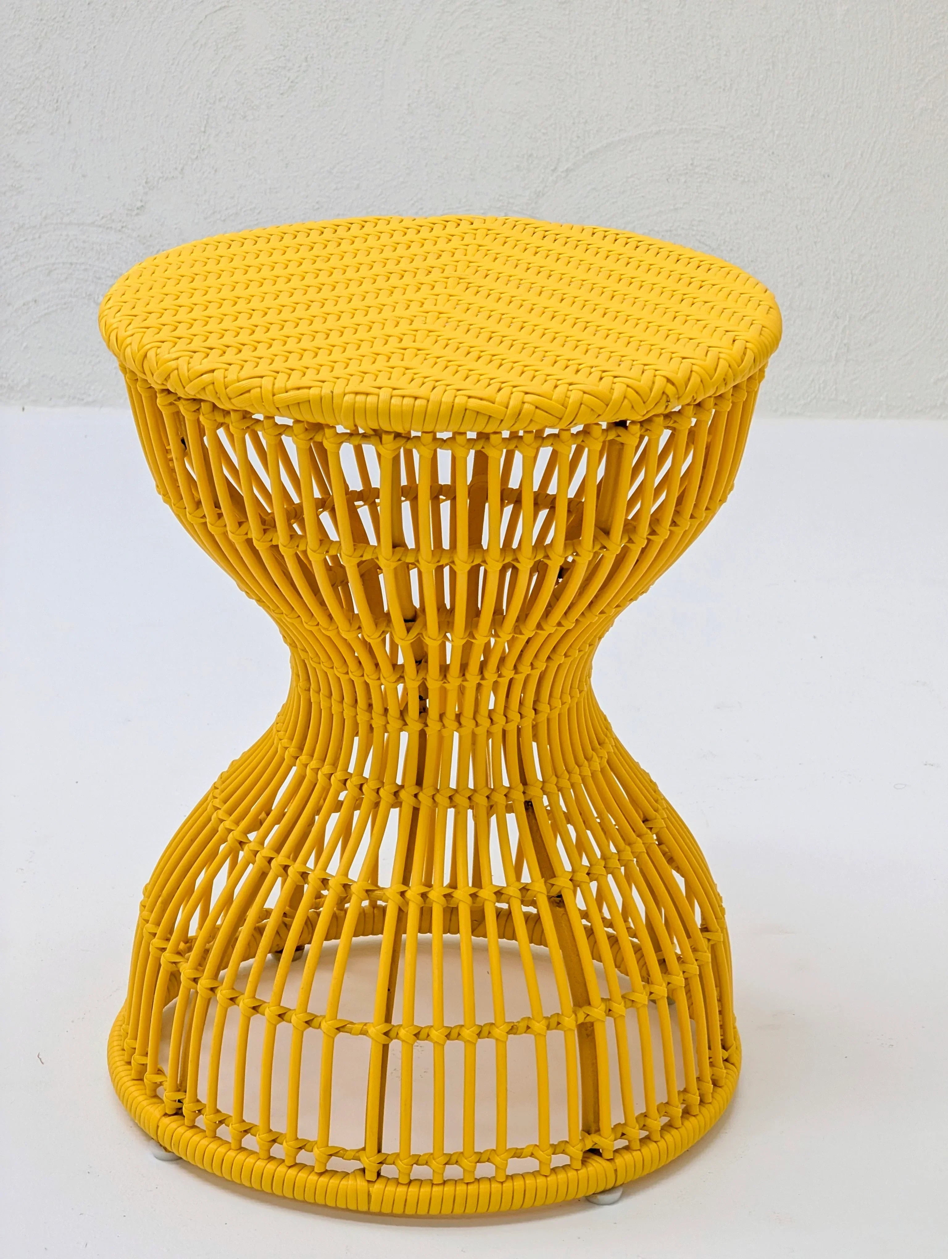 Yellow rattan hourglass side table on white background, modern woven furniture