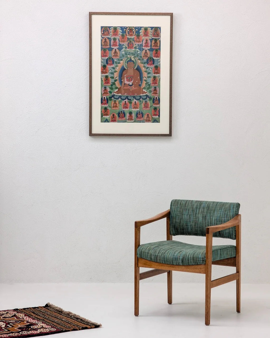 Mid-century modern wooden chair with green upholstery, Tibetan Buddha art, and oriental rug