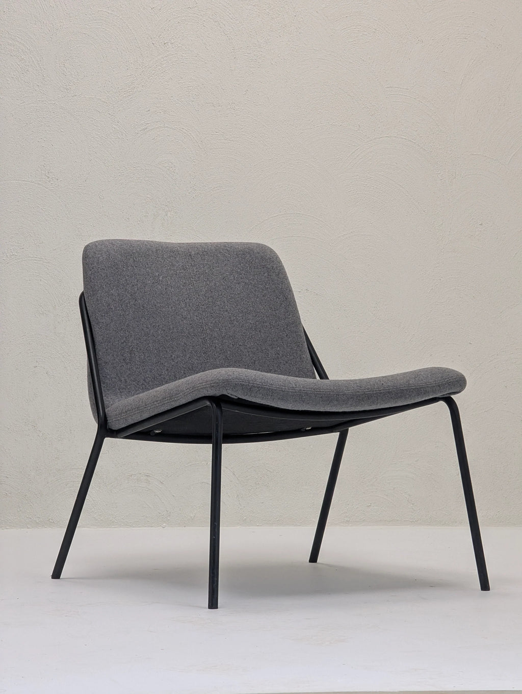 Modern lounge chair with gray upholstered seat and black metal frame in minimalist setting