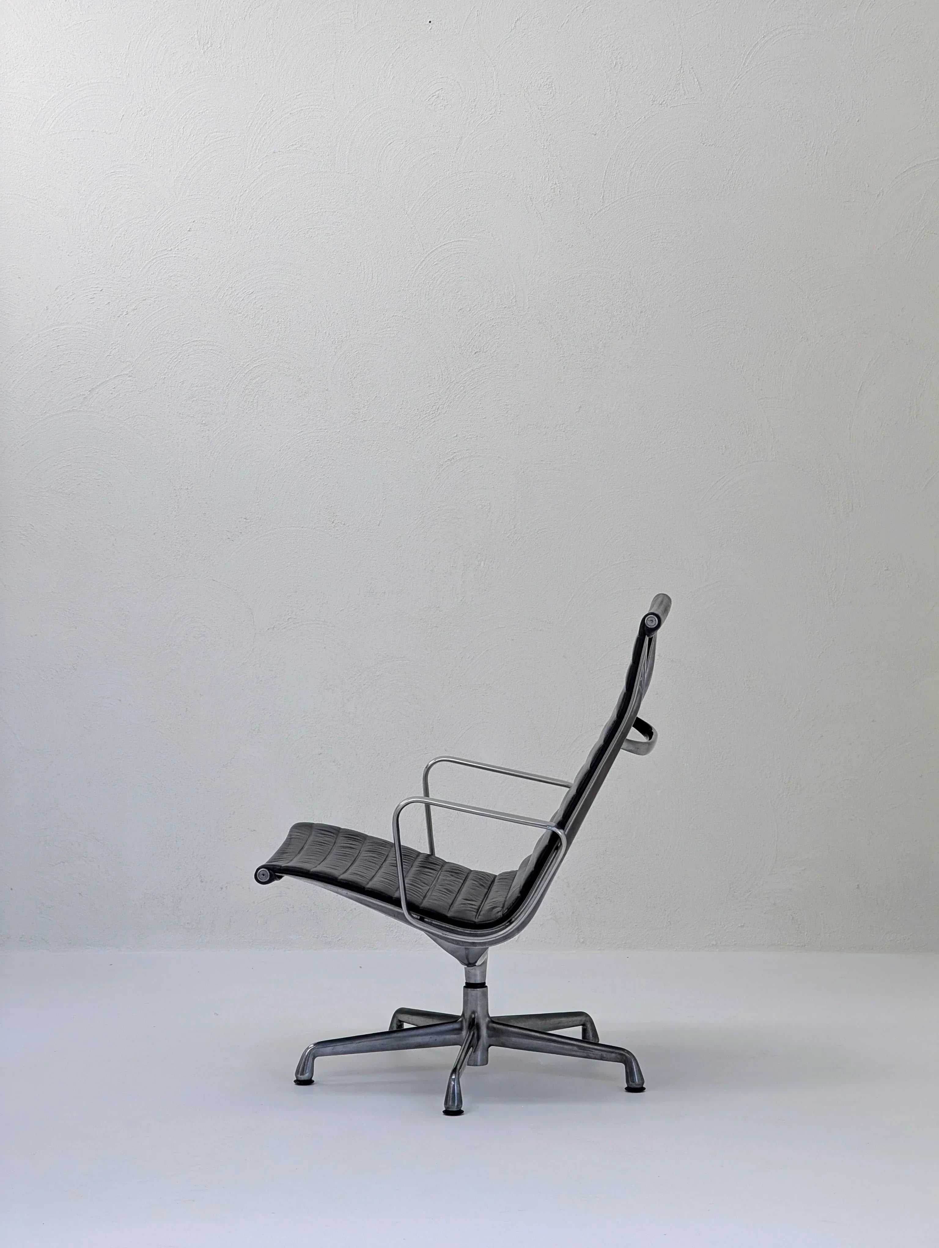 Modern black leather office chair with metal frame in minimal white room