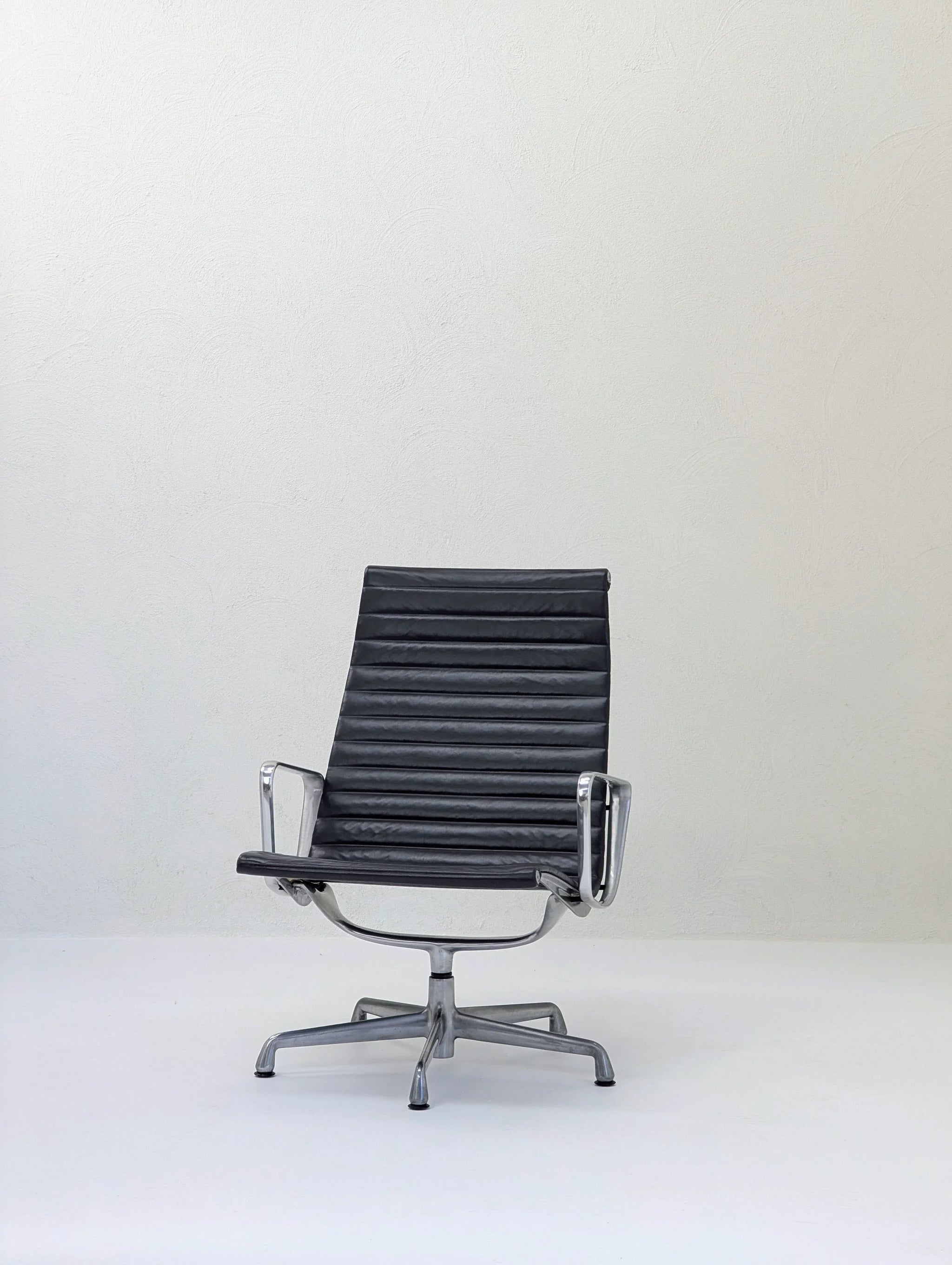 Black leather office chair with chrome arms on white background, modern ergonomic desk chair