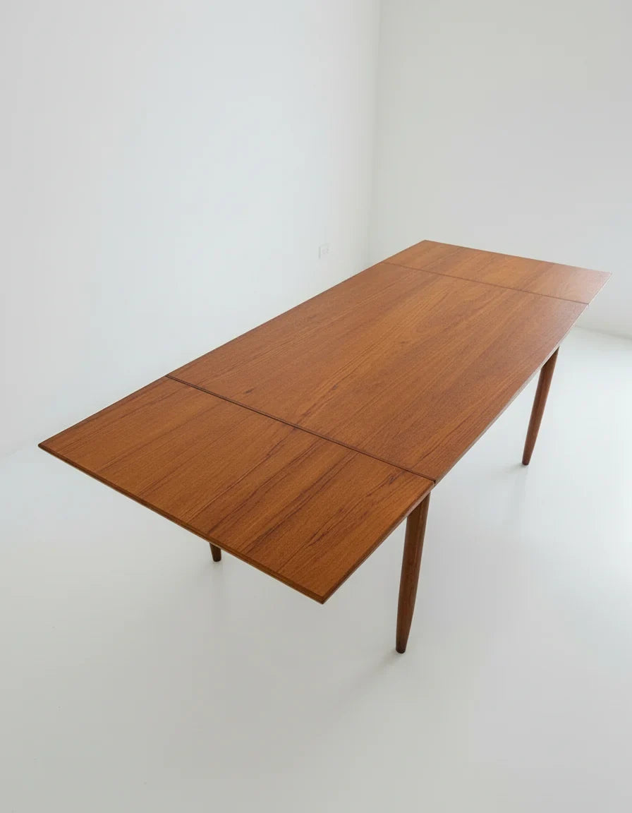 Mid-century modern teak wood dining table with tapered legs in bright white room