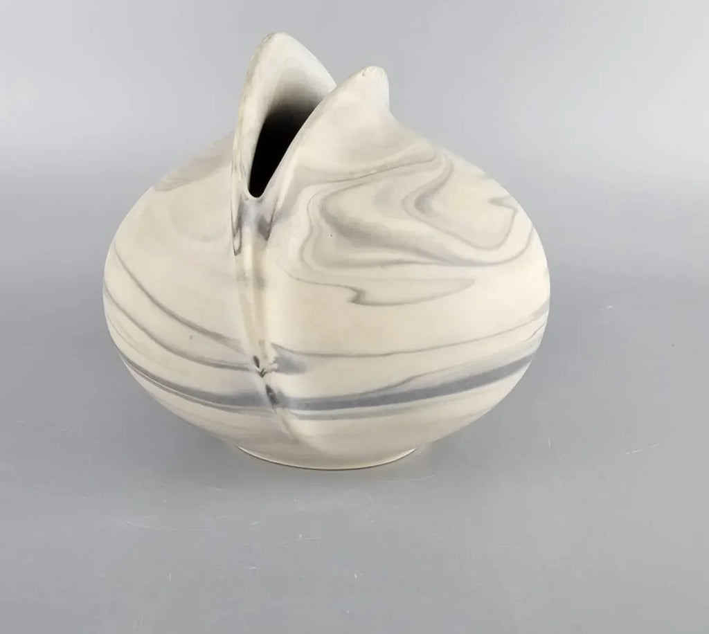 Modern marbled ceramic vase with smooth curved shape on gray background