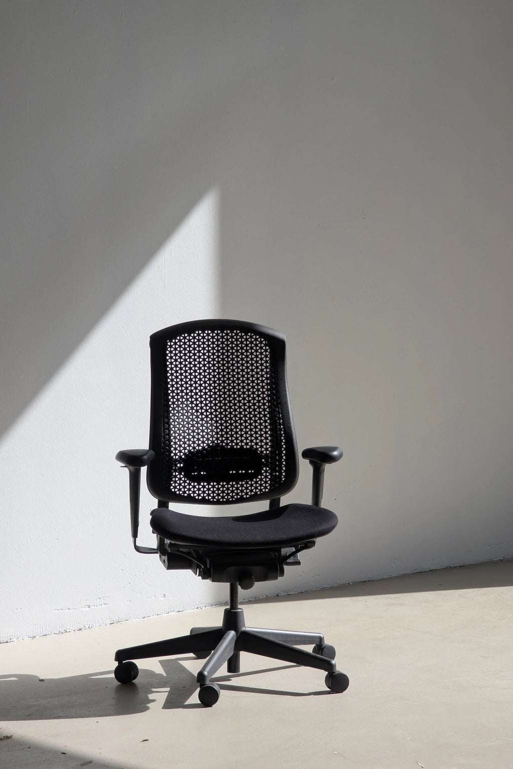 Ergonomic black office chair with mesh backrest in sunlit minimalist room