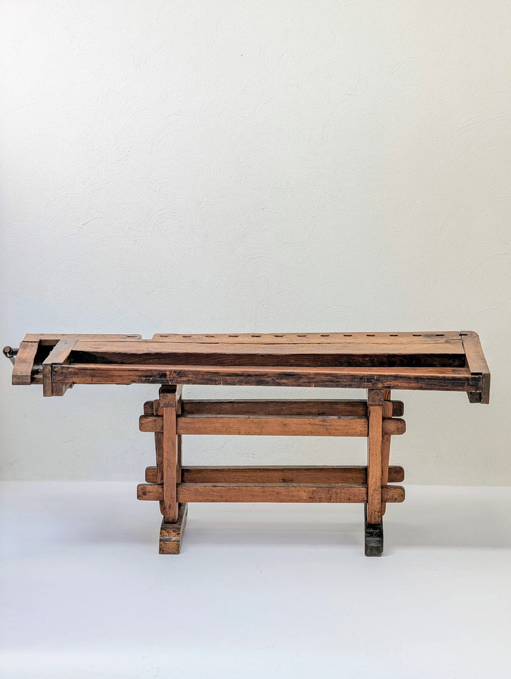 Vintage wooden workbench with vise against a plain white wall